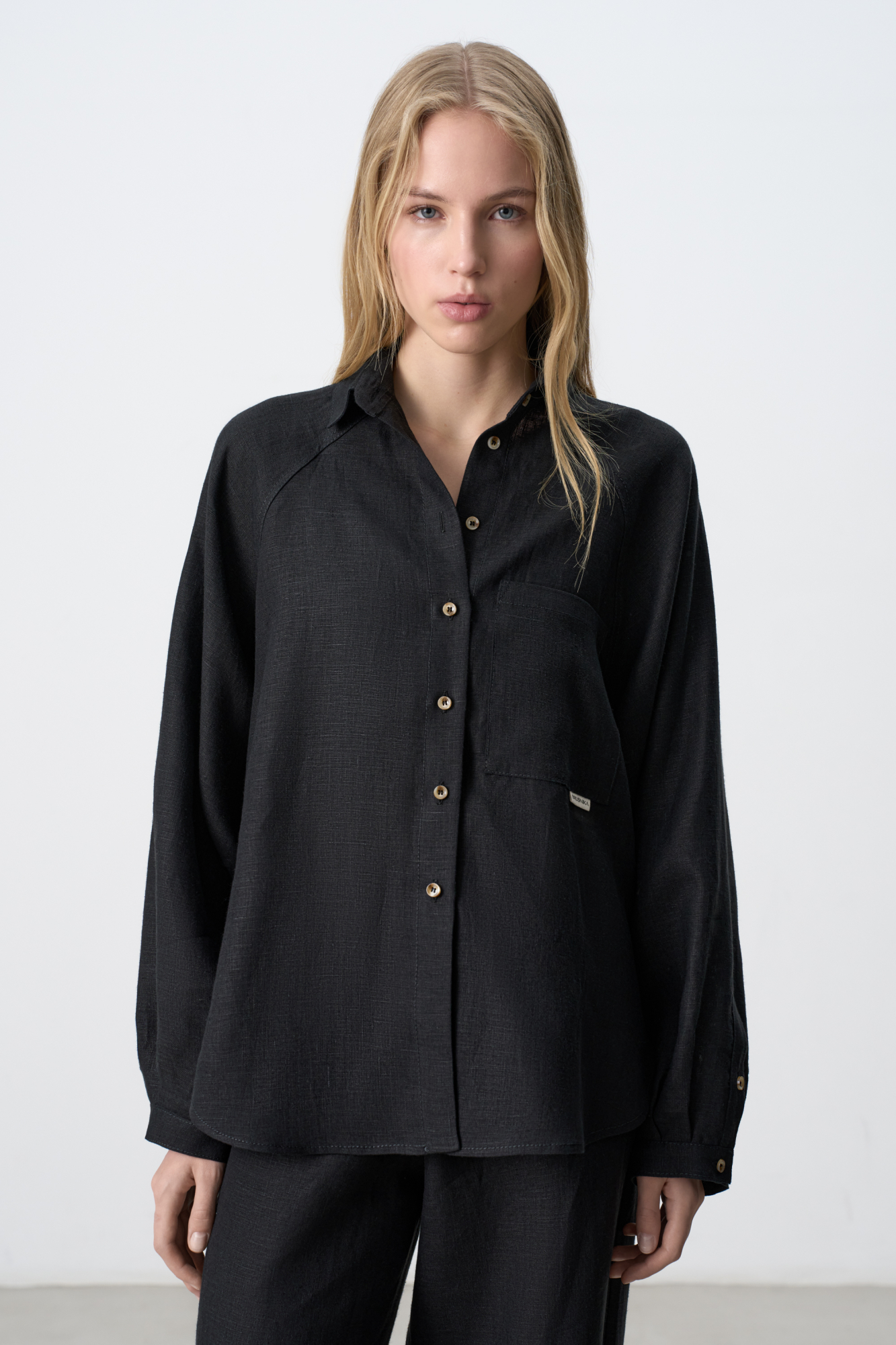 Рубашка из 100% льна с рукавом реглан. Модель свободного кроя, с длинными рукавами с короткими манжетами, классическим отложным воротником и нагрудным карманом с брендированным ярлыком. Застежка на пуговицы.