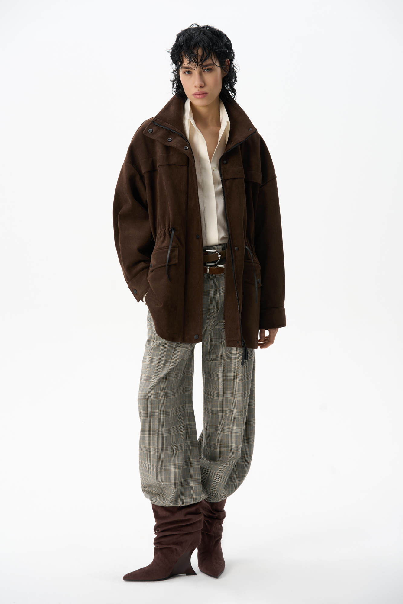 Парка, выполненная из ткани с имитацией внешнего вида и свойств натуральной замши. Модель свободного силуэта с высоким воротником-стойкой, карманами с клапанами и кулиской на талии. Застежка на молнию и магнитные кнопки на планке. Изделие выполнено на подкладке.