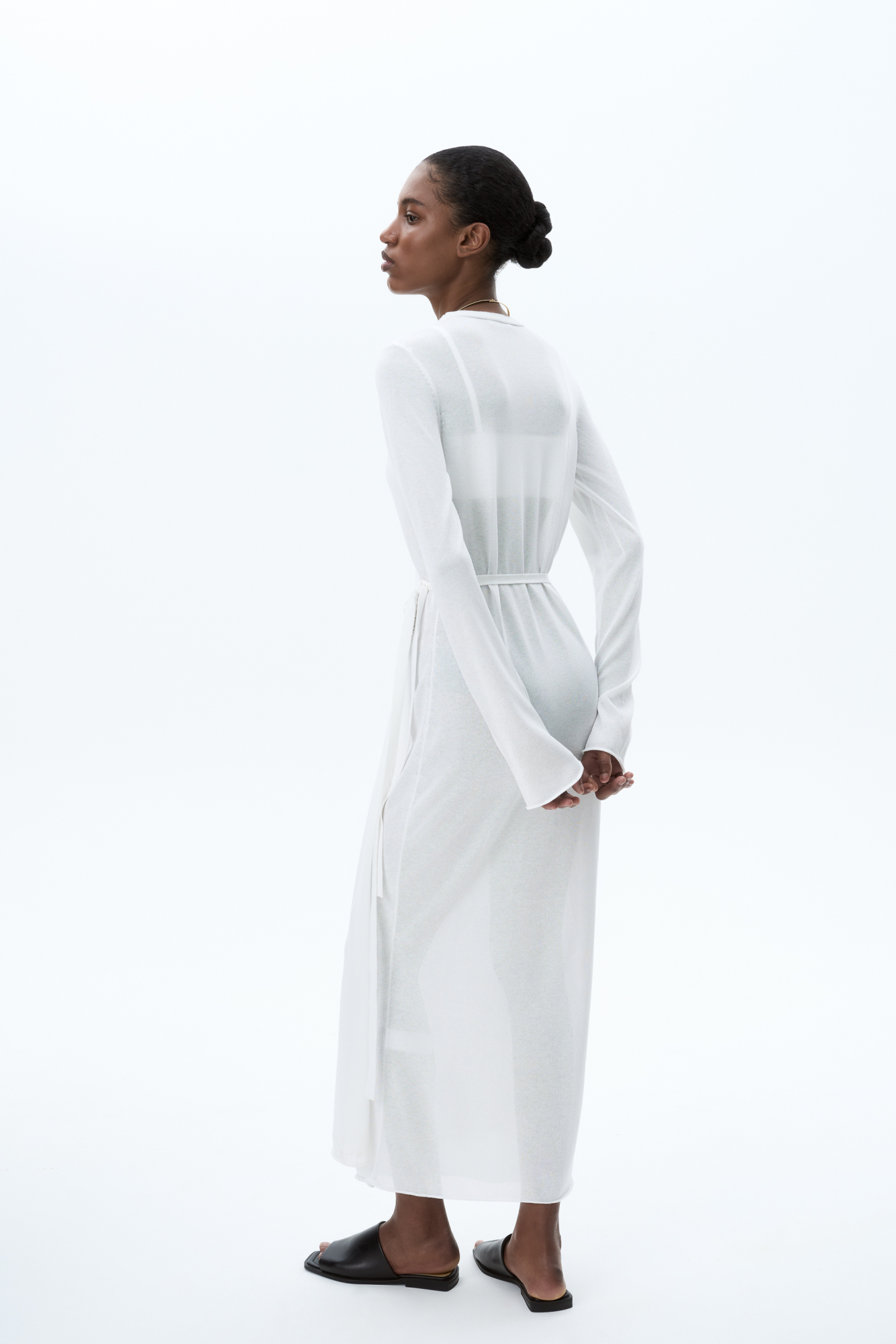 Трикотажное платье длины миди из тонкой вискозы. Модель приталенного силуэта на запах, с V-образным вырезом горловины, длинными расклешенными рукавами и кулиской на талии.