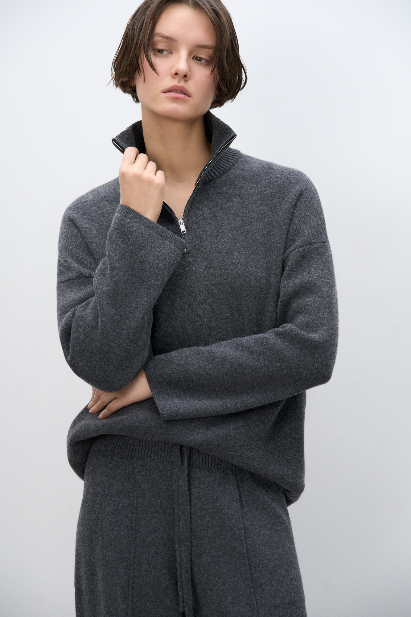 Трикотажный джемпер из кашемира и шерсти. Модель свободного кроя, с высоким воротом на молнии и спущенной линией плеч. Ворот и края изделия выполнены в рубчик.