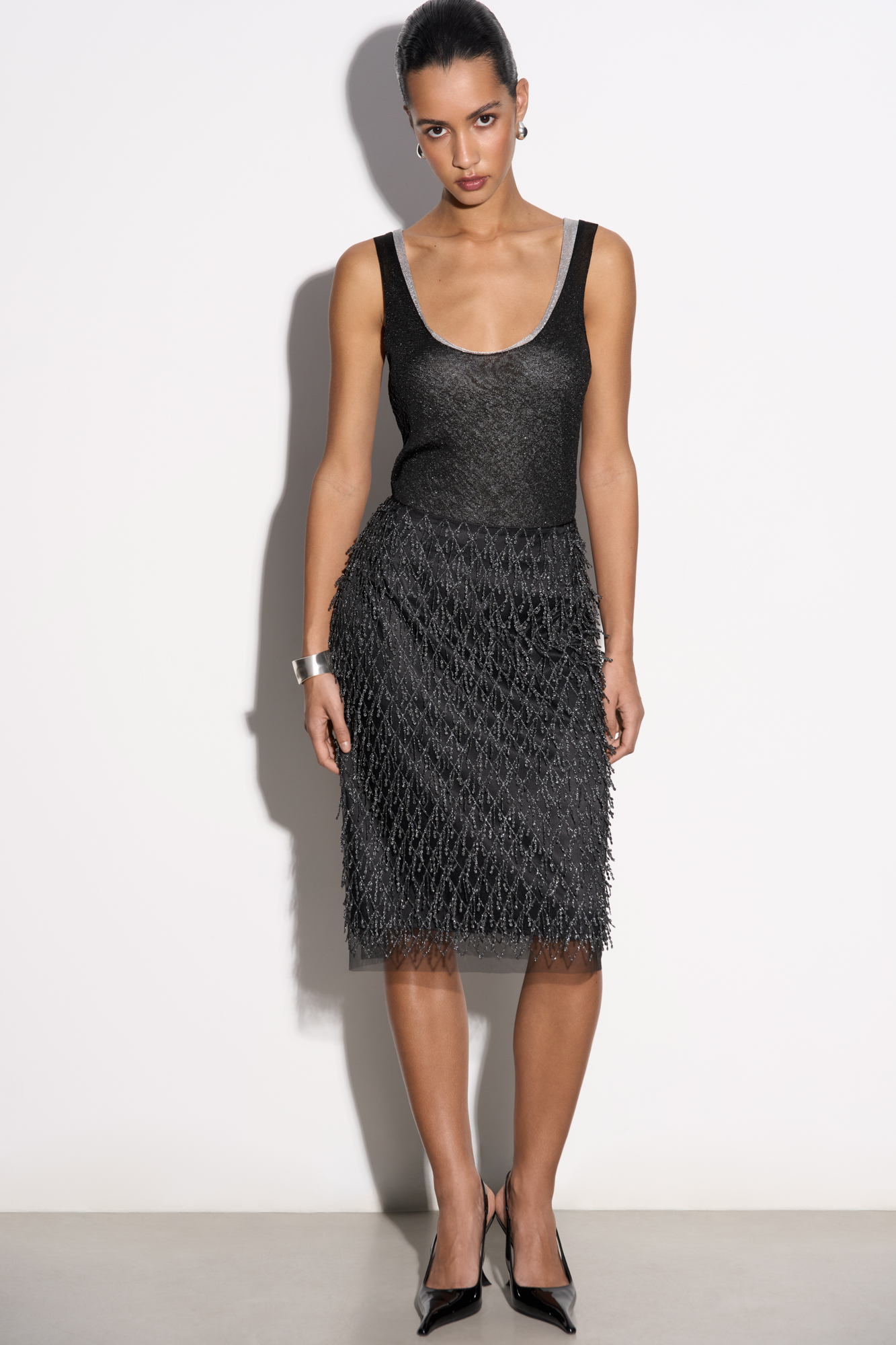 Юбка длины миди с объемным геометрическим дизайном и бахромой. Застежка на молнию сзади. Изделие выполнено на подкладке.