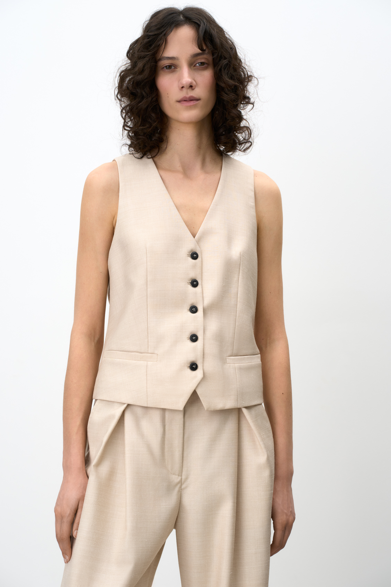 Классический жилет из шерсти с текстурой. Модель прямого кроя с V-образным вырезом и имитацией карманов. Застежка на пуговицы. Дополнить образ можно жакетом и брюками в таком же стиле.