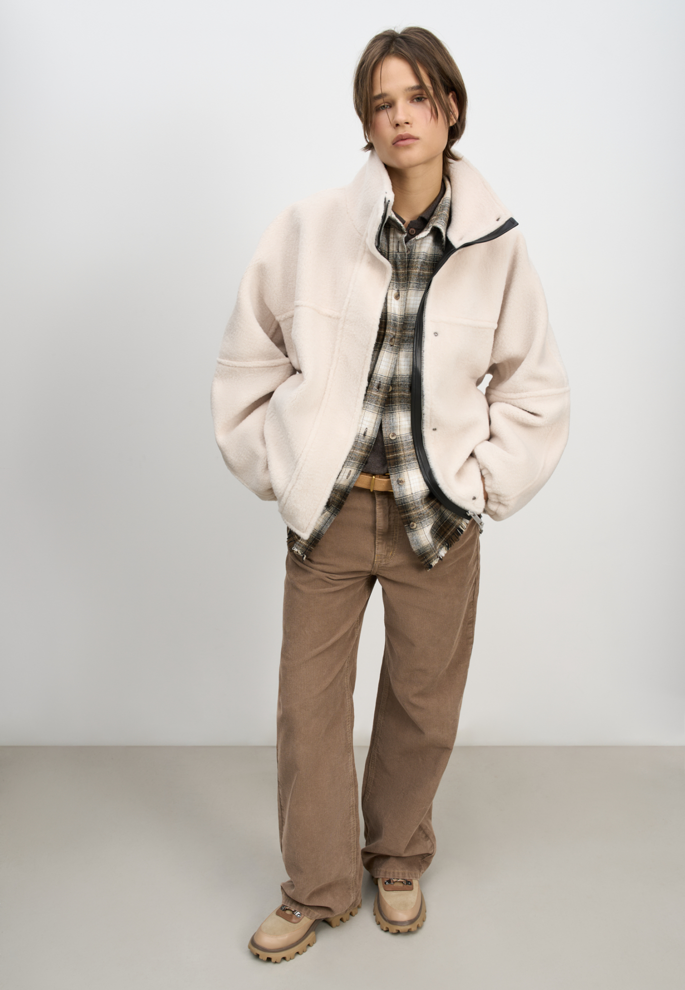 Шуба из экомеха с воротником-стойкой. Модель свободного силуэта с боковыми карманами, объемными швами и манжетами на резинке. Застежка на молнию под планкой с кнопками, декорированной экокожей.