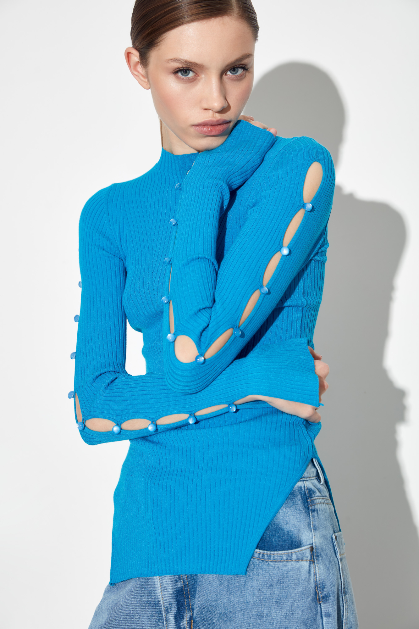 Трикотажный топ из вискозы. Модель приталенного силуэта, разрезами по бокам, с длинными рукавами на пуговицах, невысоким воротником-стойкой и декоративными сбавками на груди.