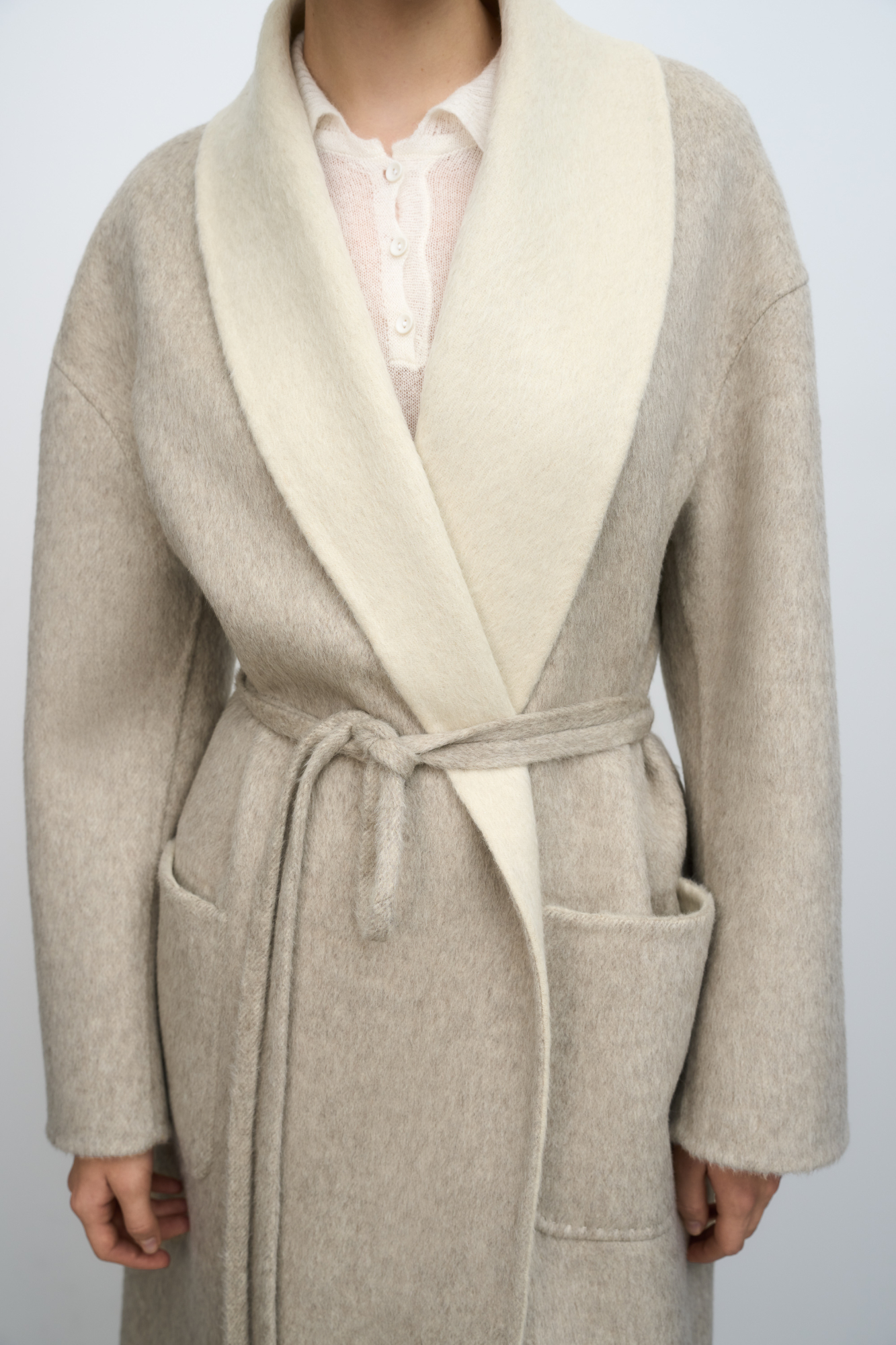 Пальто-халат из двусторонней ткани. В составе 80% шерсти с добавлением 10% ангоры и 10% шелка. Отложной воротник, накладные карманы и тонкий ремень в тон основной ткани. При пошиве этого изделия была использована технология double face, благодаря которой внутренняя сторона выглядит также аккуратно, как и внешняя.