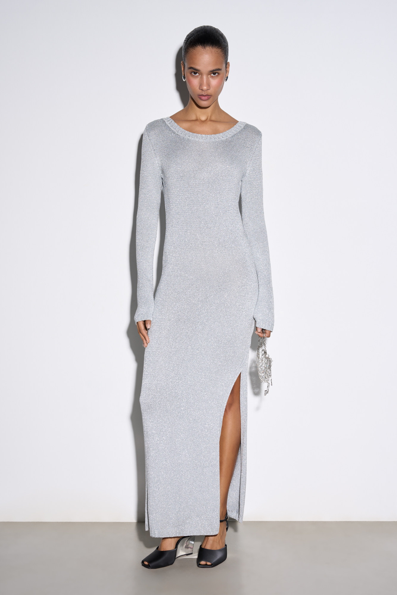 Трикотажное платье длины макси из вискозы с добавлением люрекса. Модель по фигуре с длинными рукавами, круглым вырезом горловины, вырезом на спине и разрезом на подоле сбоку. Края изделия выполнены в рубчик. 