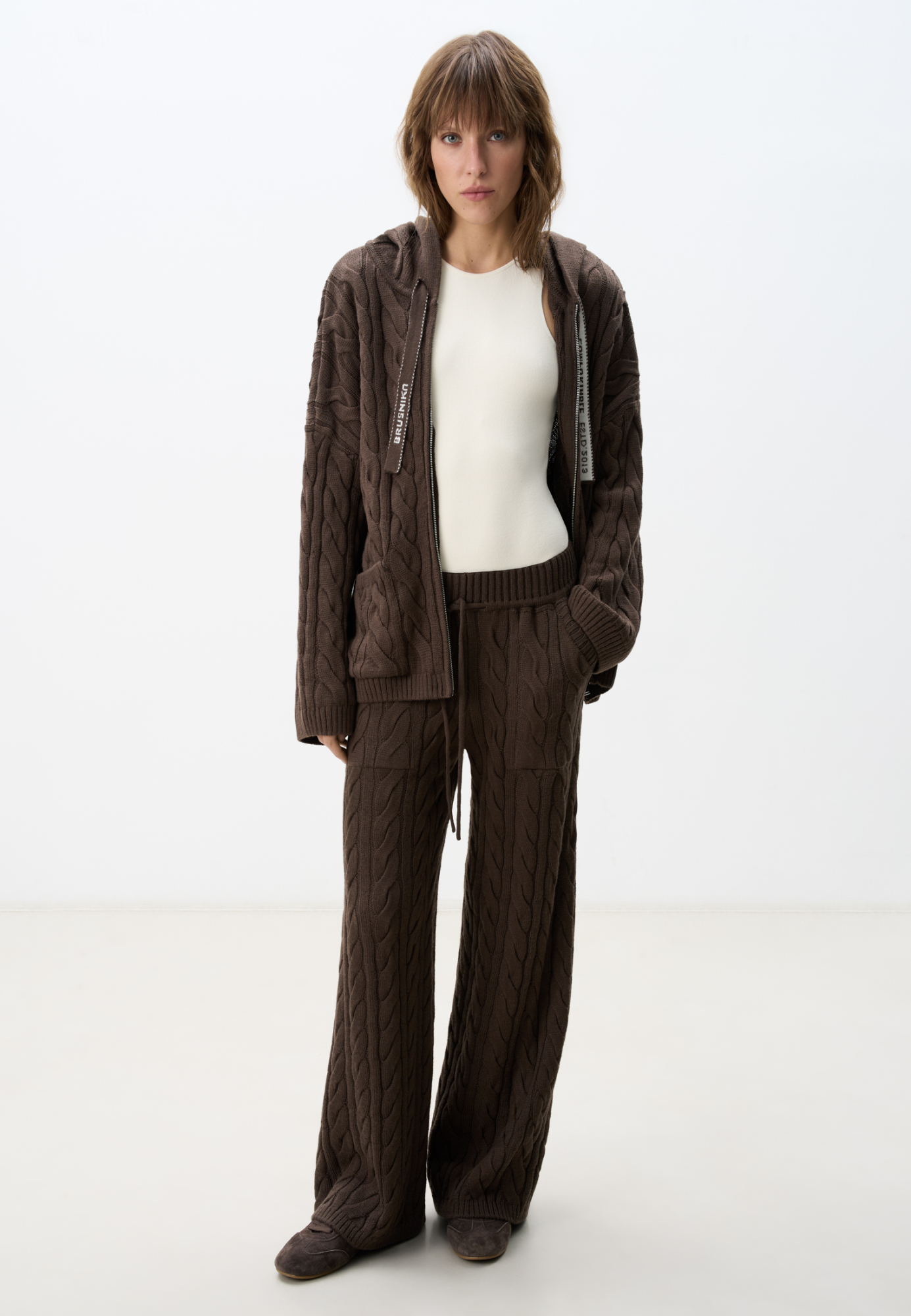 Прямые трикотажные брюки с объемными косами из мягкой шерсти. Широкий эластичный пояс на кулиске, передние и задние карманы и манжеты внизу. Дополнить образ можно джемпером в том же стиле.