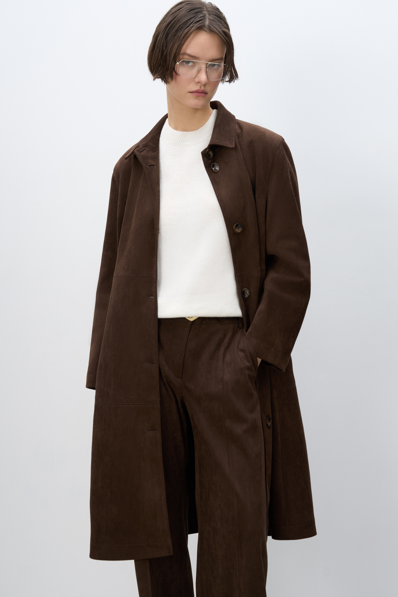 Тренч из ткани с имитацией внешнего вида и свойств натуральной замши. Модель прямого кроя с отложным воротником. Застежка на крупные пуговицы. 