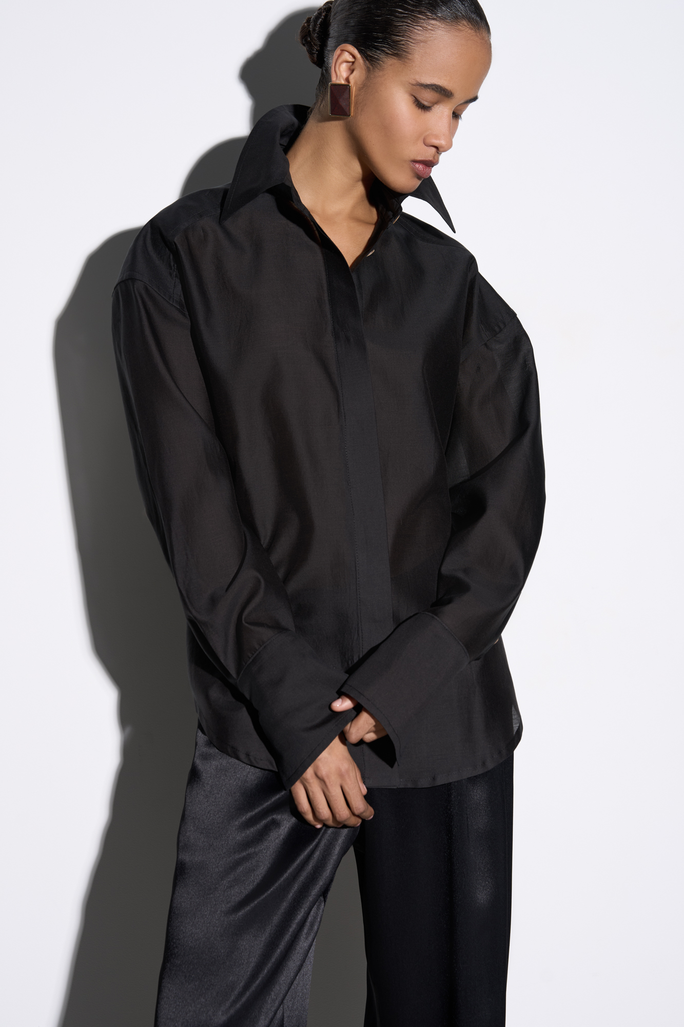 Рубашка из шелка с добавлением хлопка. Модель прямого кроя с длинными рукавами с манжетами, классическим отложным воротником, увеличенными плечами и завязкой на спинке. Застежка на пуговицы под планкой.