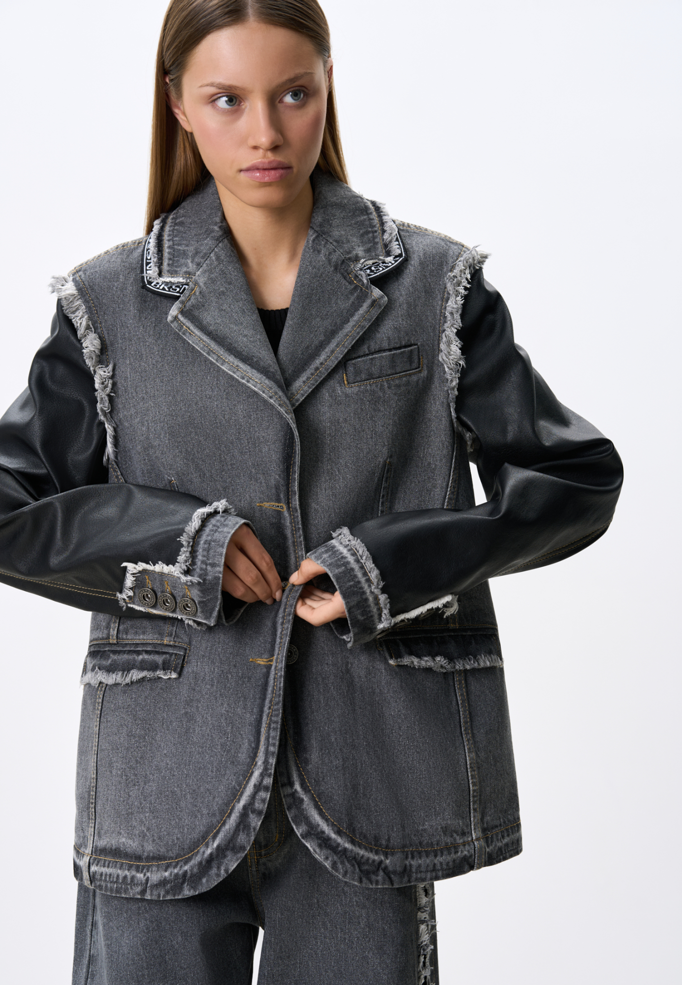 Джинсовый однобортный жакет из хлопка с деталями из экокожи. Модель прямого силуэта, со спущенной линией плеча, с отложным воротником, боковыми и нагрудными карманами. Изделие декорировано рваной текстурой. Без подкладки. Застежка на металлические пуговицы.