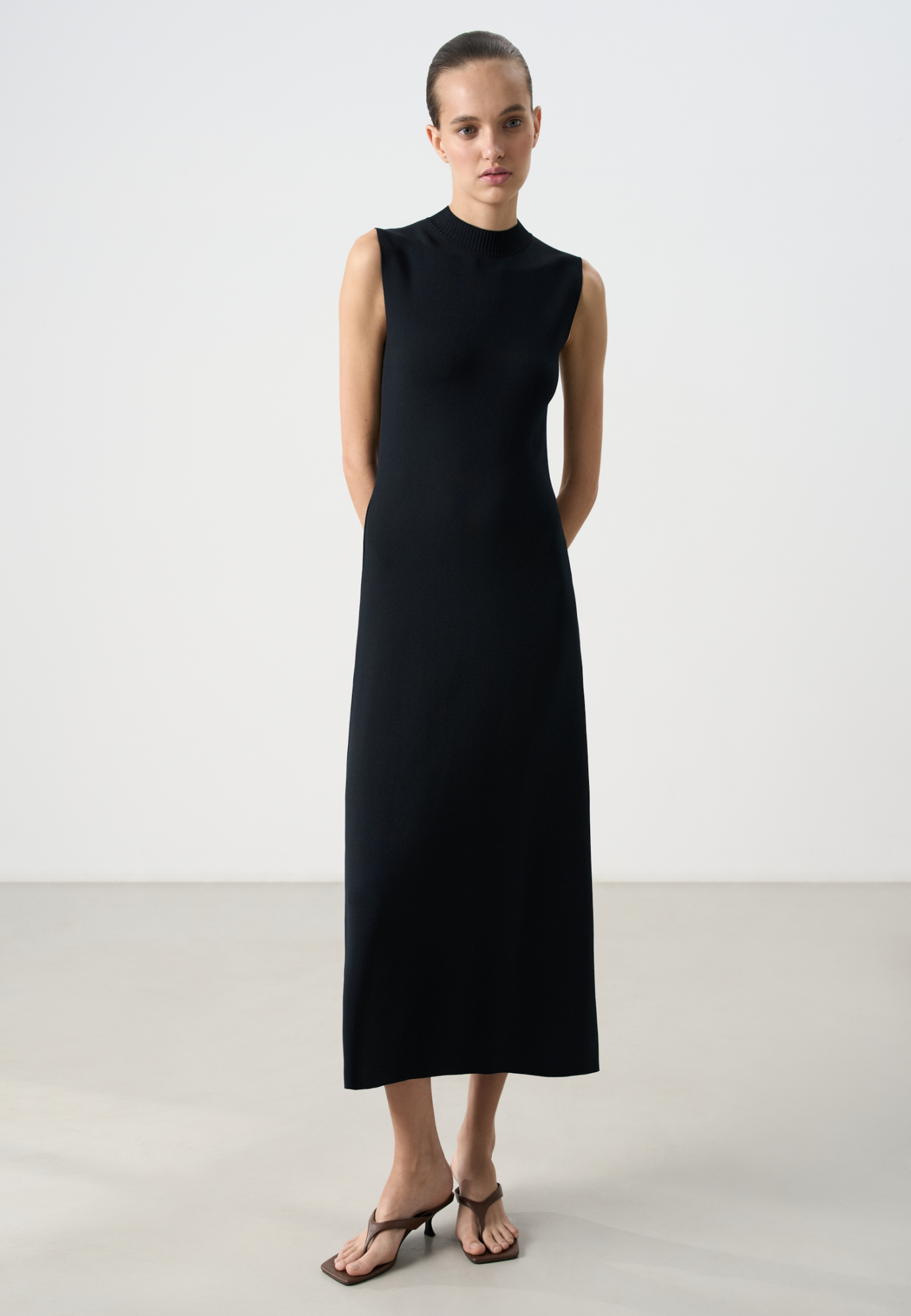 Трикотажное платье длины миди из вискозы. Модель приталенного силуэта, без рукавов, с невысоким воротником стойкой.
