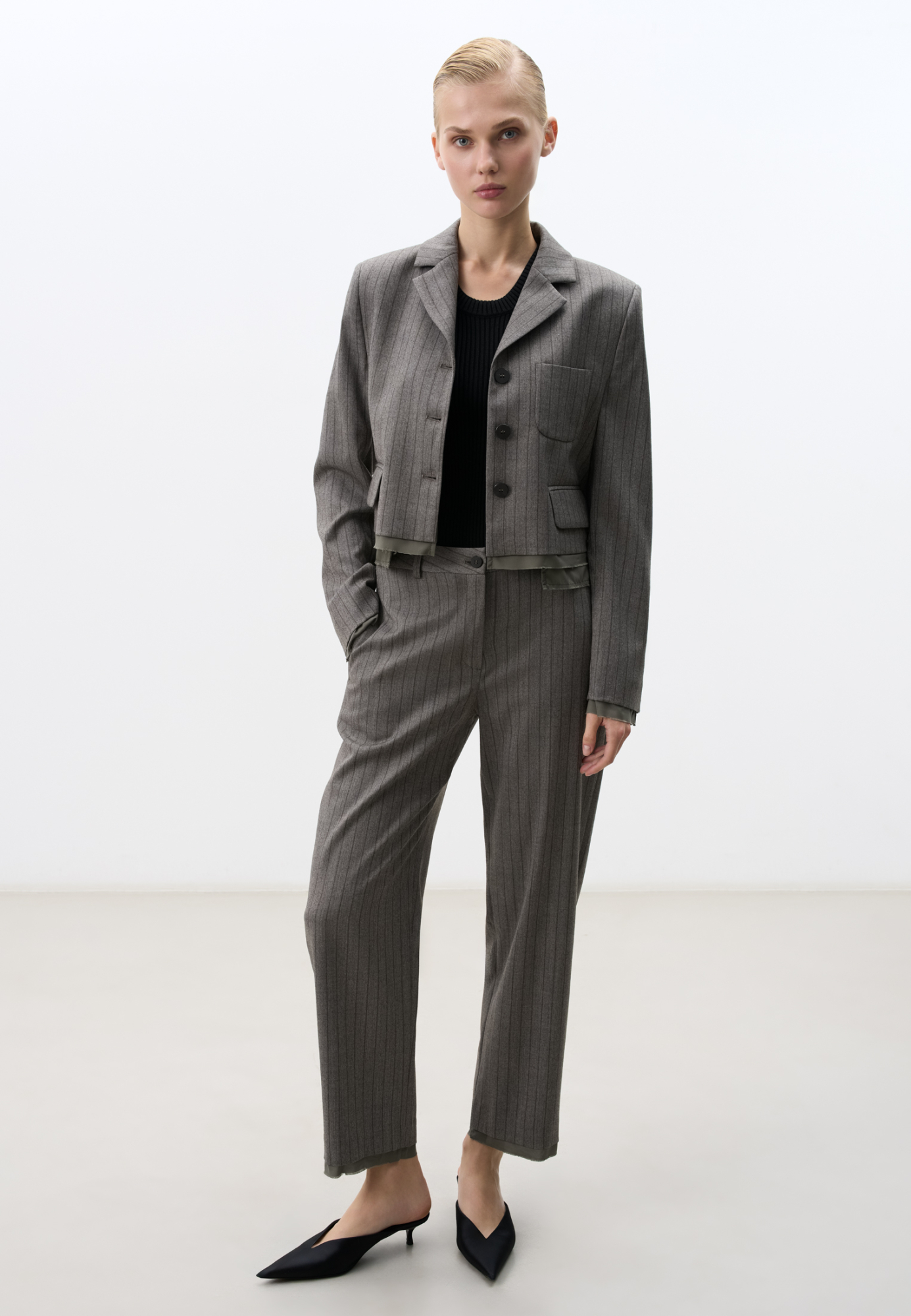 Брюки из шерсти в полоску. Модель прямого кроя, на средней посадке, с боковыми и задними карманами. Имитация торчащей подкладки внизу издедия. Застежка на молнию и пуговицу. Дополнить образ можно жакетом в таком же стиле.
