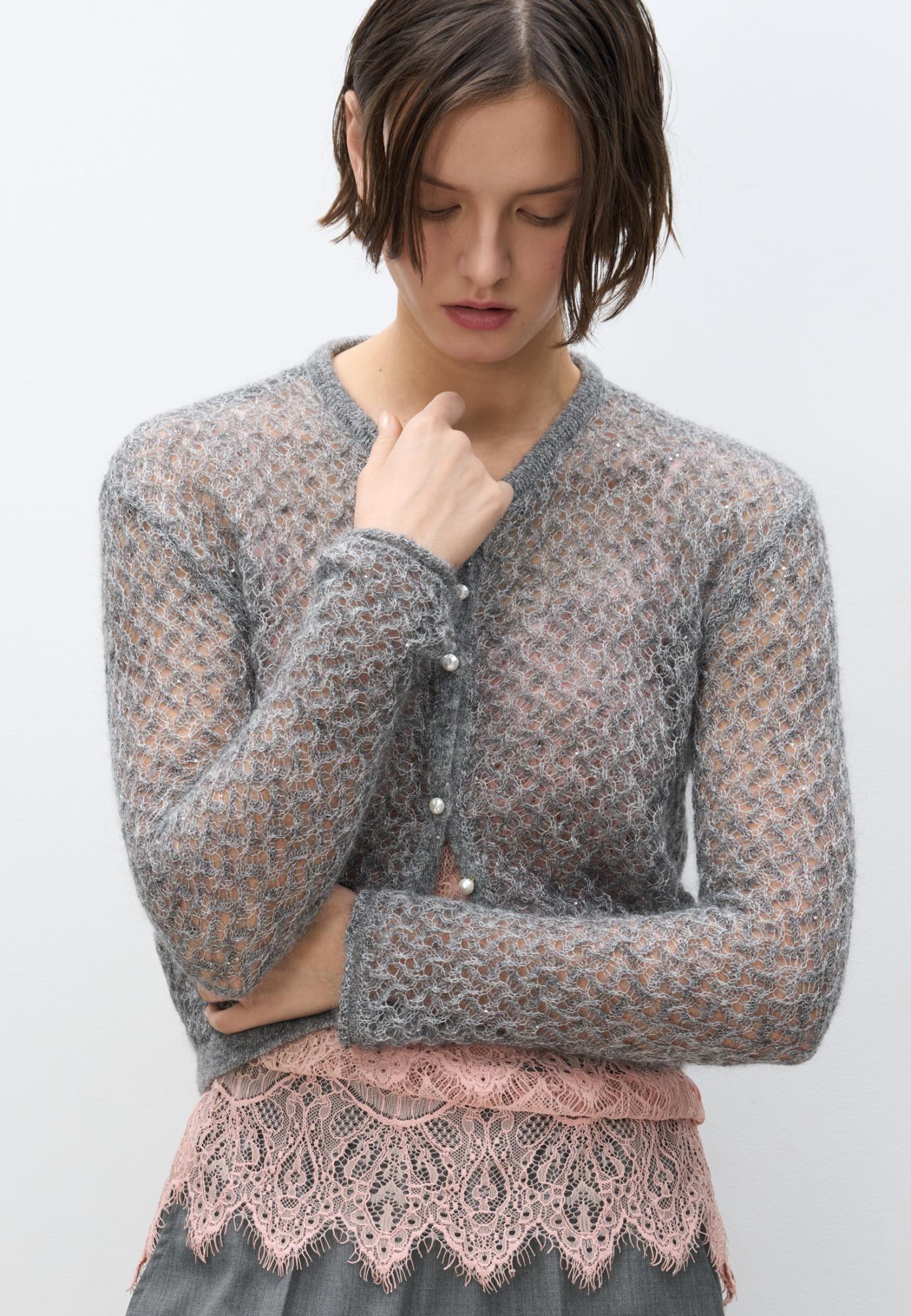 Трикотажный ажурный кардиган из кидмохера, декорированный мелкими пайетками. Модель свободного силуэта с длинными рукавами, круглым вырезом горловины и застежкой на жемчужные пуговицы. 