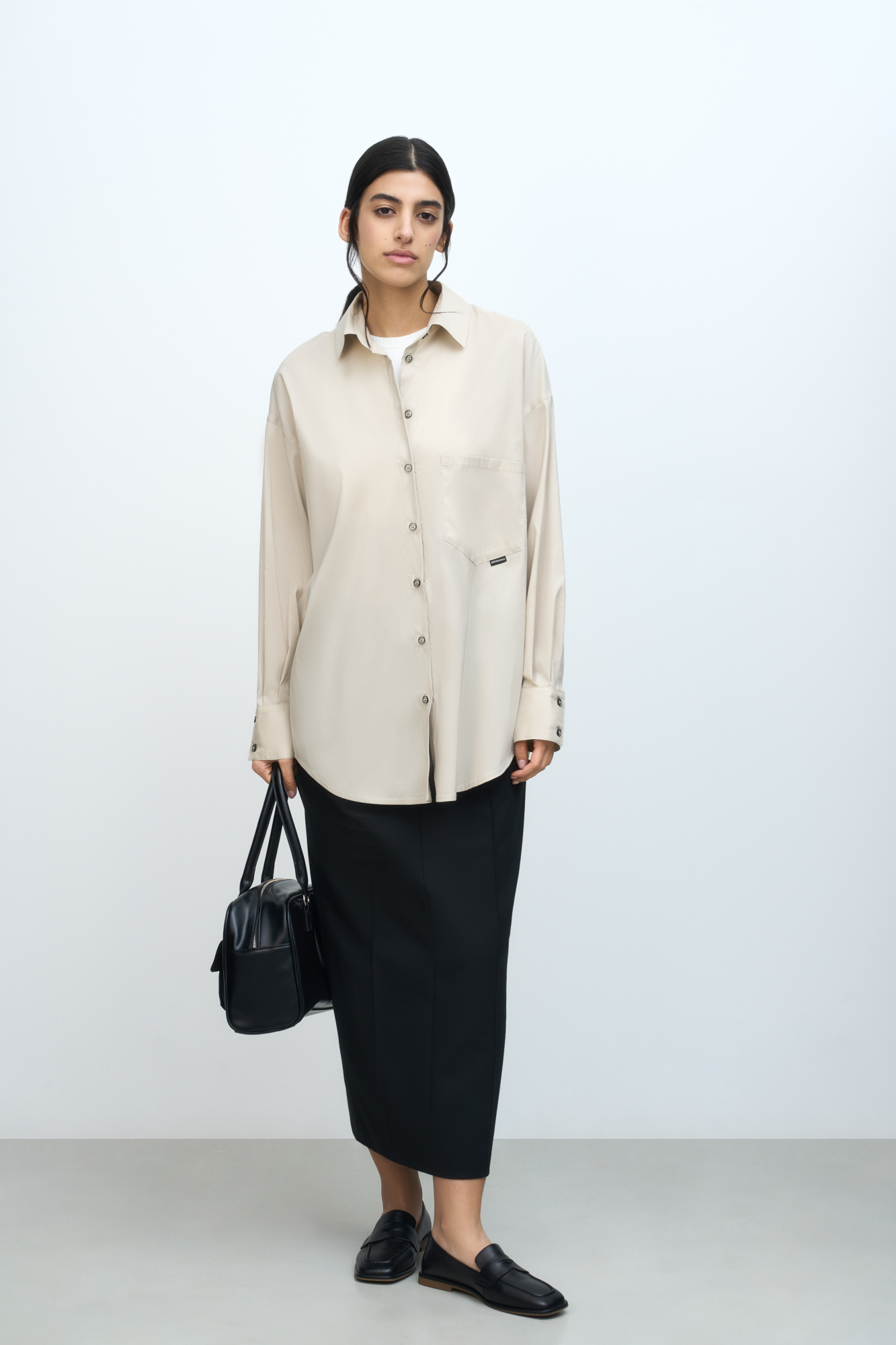 Рубашка с накладным карманом и брендированным ярлыком. Модель свободного силуэта, длинные рукава с манжетами и асимметричный нижний край.