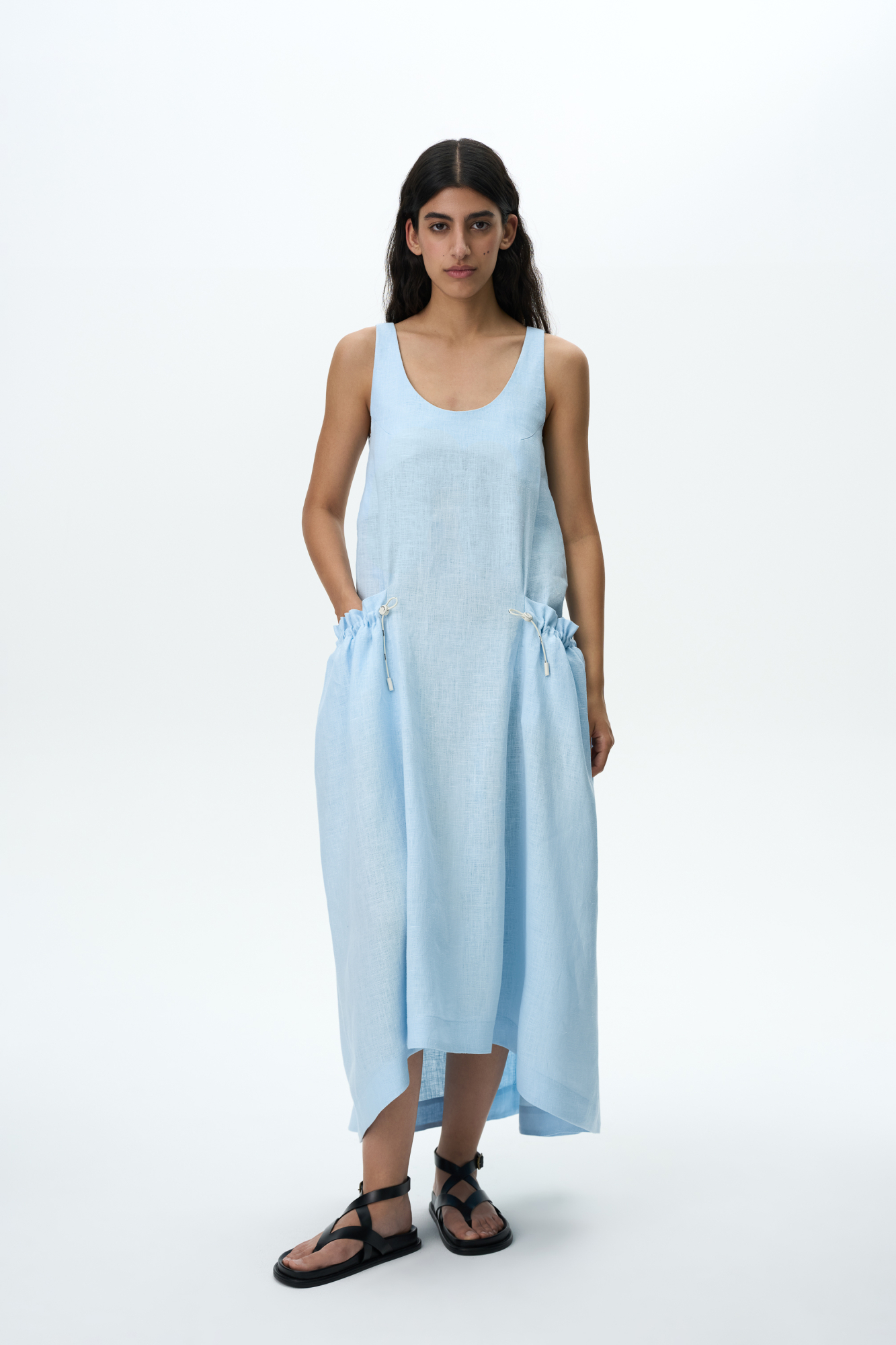 Платье из 100% льна с регулируемой кулиской на поясе. Модель свободного силуэта, без рукавов, на широких лямках, с U-вырезом горловины и боковыми карманами.