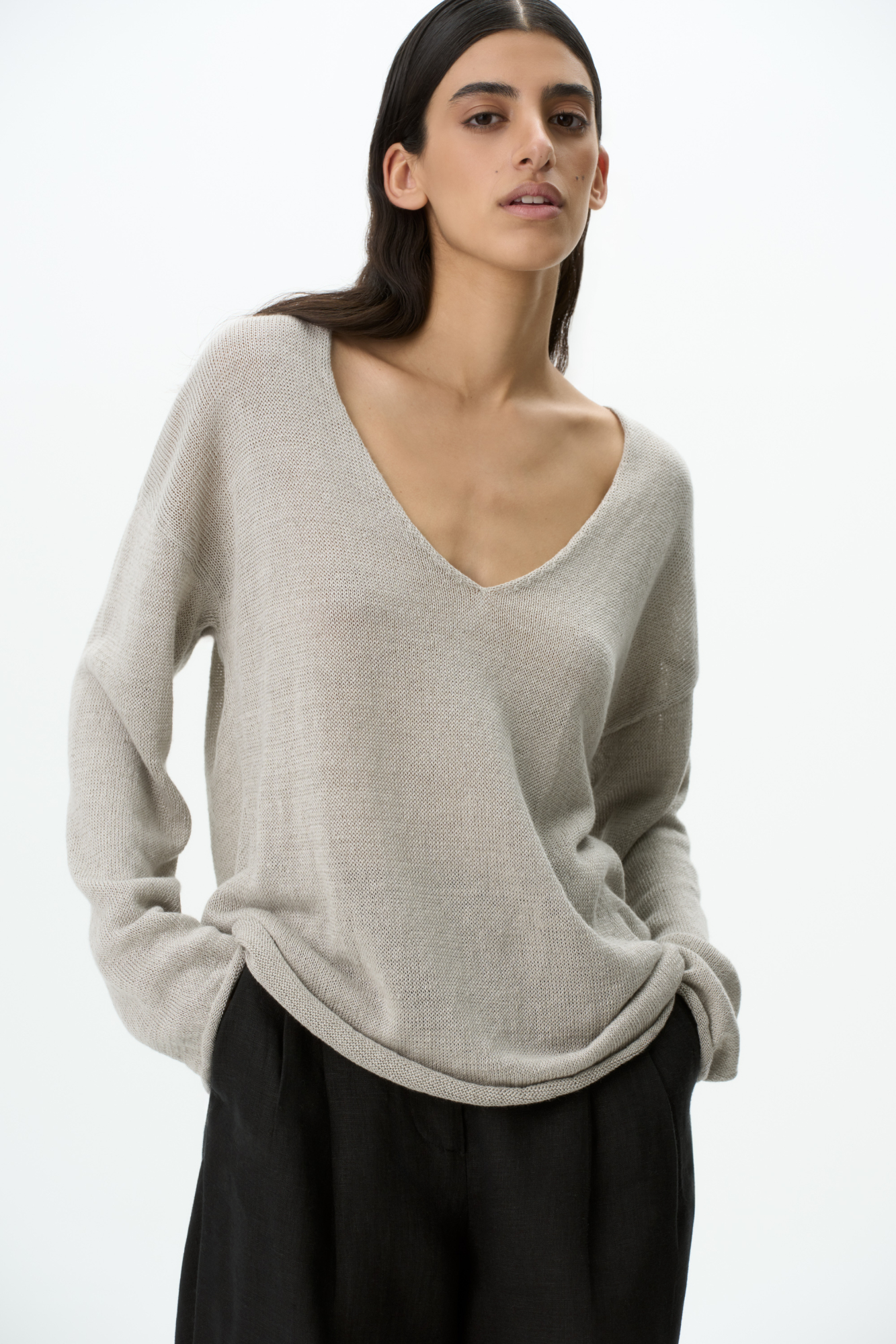 Трикотажный джемпер из 100% льна. Модель свободного силуэта с длинным рукавом и с V-образным вырезом горловины. Изделие декорировано брендированным ярлыком сбоку и валиками по низу.