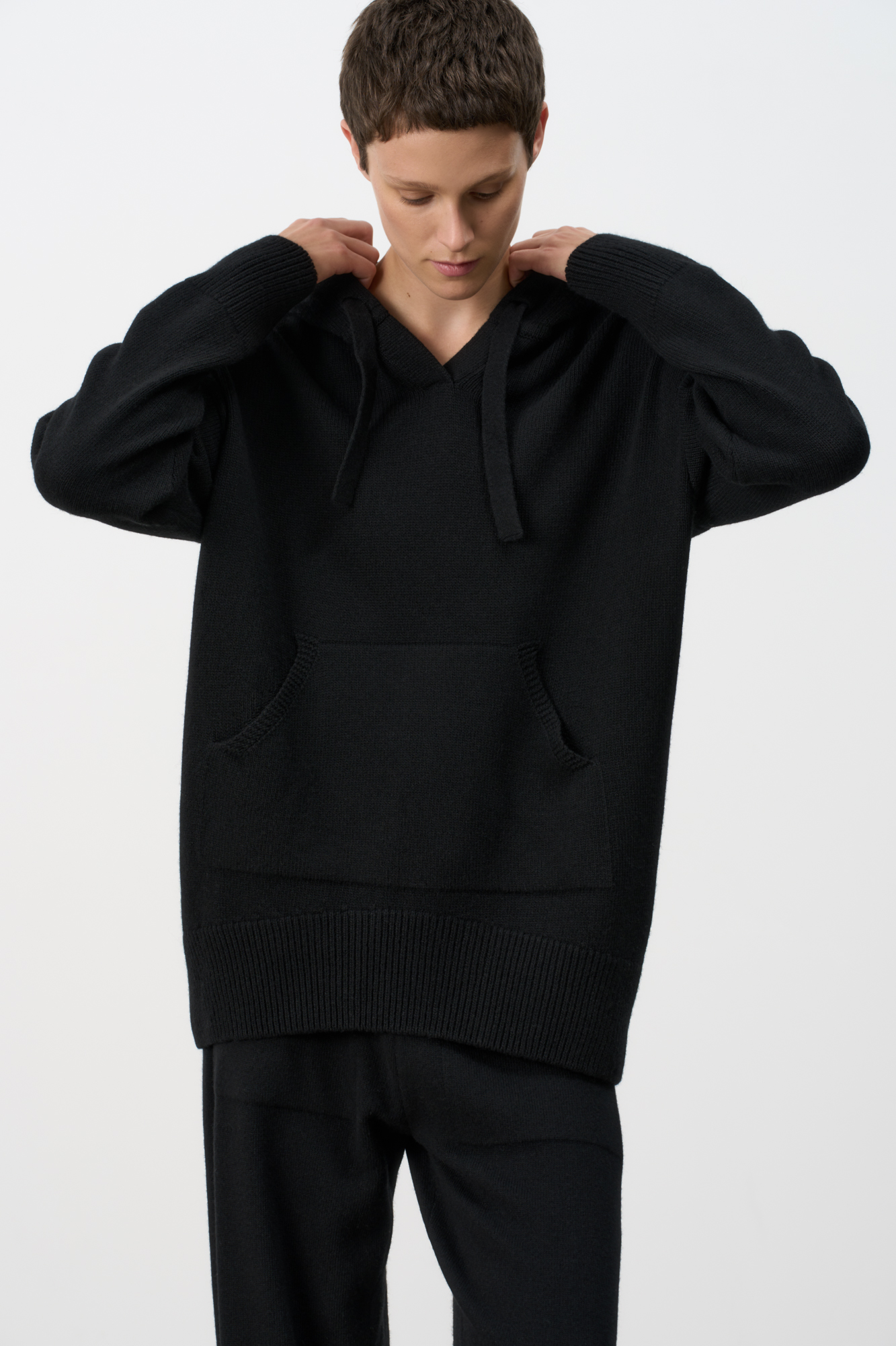 Трикотажное худи из кашемира и шерсти. Модель свободного силуэта, со спущенной линией плеч, глубоким капюшоном на кулиске и карманом-кенгуру. Края изделия выполнены в рубчик.