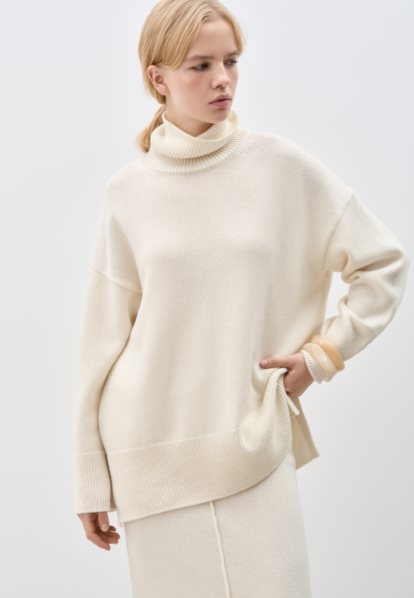 Трикотажный джемпер из кашемира и шерсти. Модель свободного силуэта, со спущенной линией плеч и высоким вывязанным воротом. Манжеты рукавов и низ изделия выполнены в рубчик. 