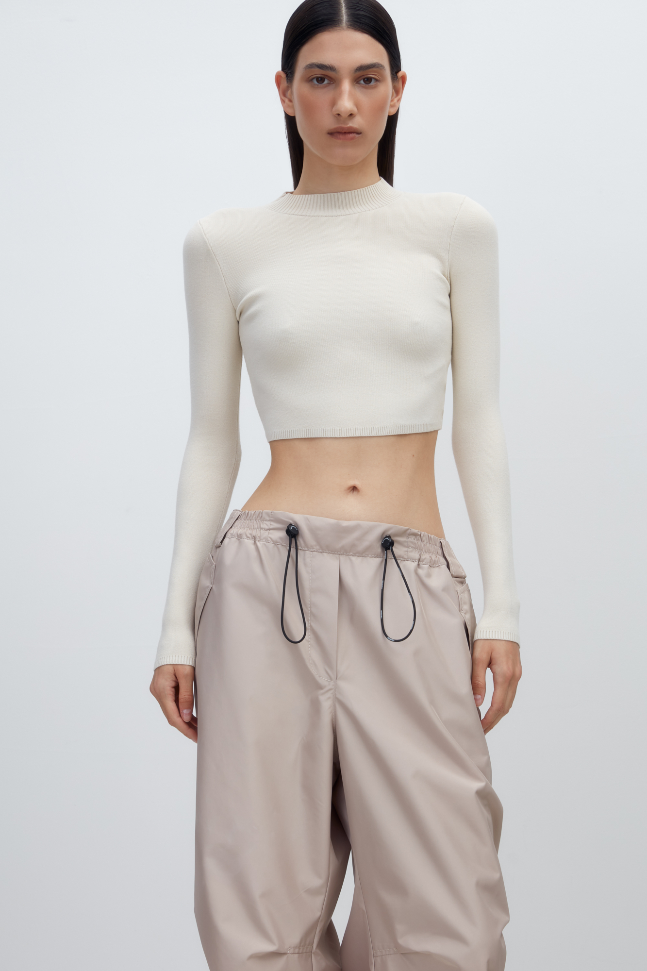 Трикотажный кроп-топ из вискозы с длинным рукавом, круглым вырезом горловины и фигурным низом. Края изделия выполнены в рубчик.