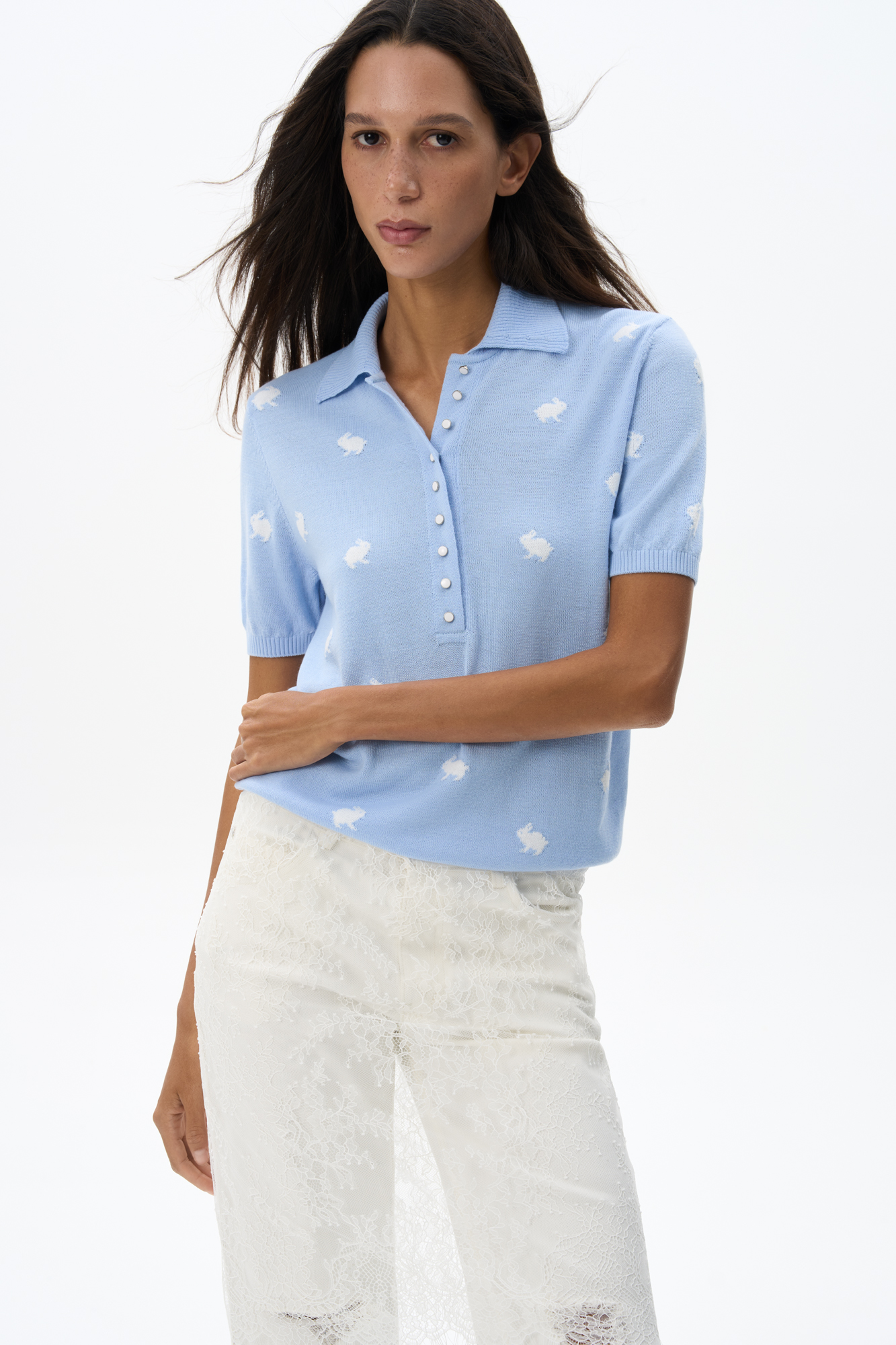 Трикотажная футболка из шерсти. Модель свободного кроя с воротником поло и застежкой на маленькие пуговицы на планке. Изделие декорировано жаккардом в виде зайчиков.