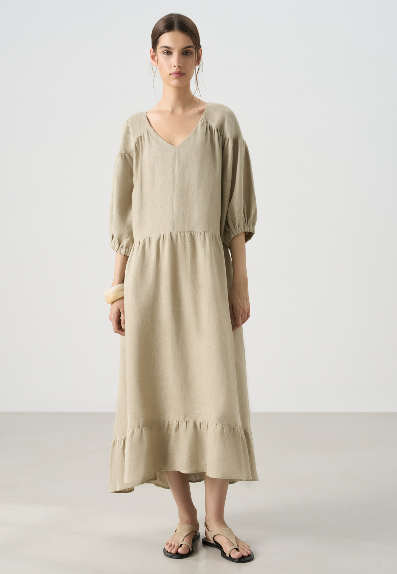 Длинное платье из 100% льна с расклешением от талии и широким асимметричным воланом внизу. Короткий рукав на резинке. V-образный вырез с завязками на спине.