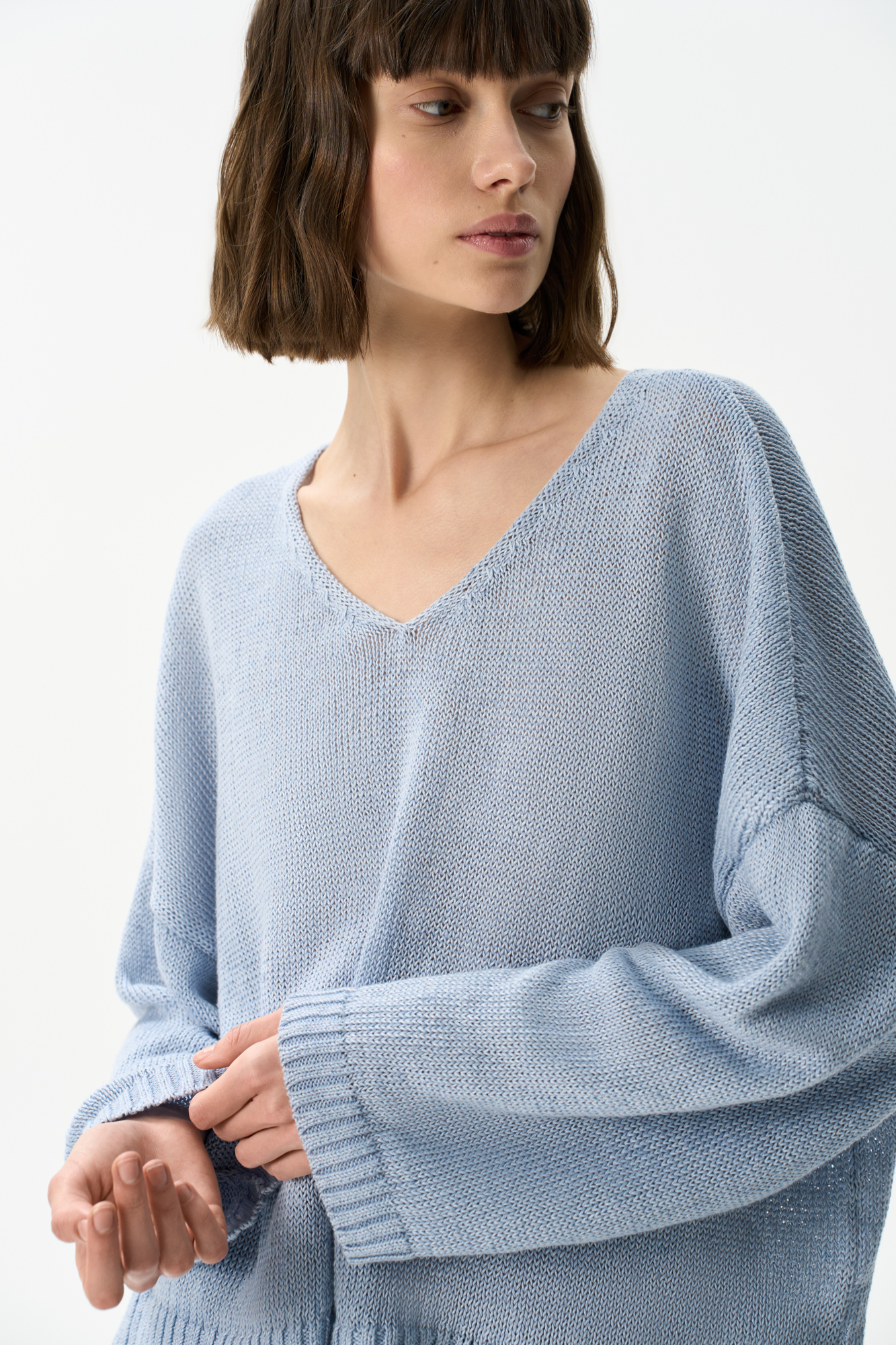 Трикотажный джемпер из 100% льна с V-образным вырезом. Модель прямого силуэта с длинным рукавом и удлиненной спинкой. Края изделия выполнены в рубчик.