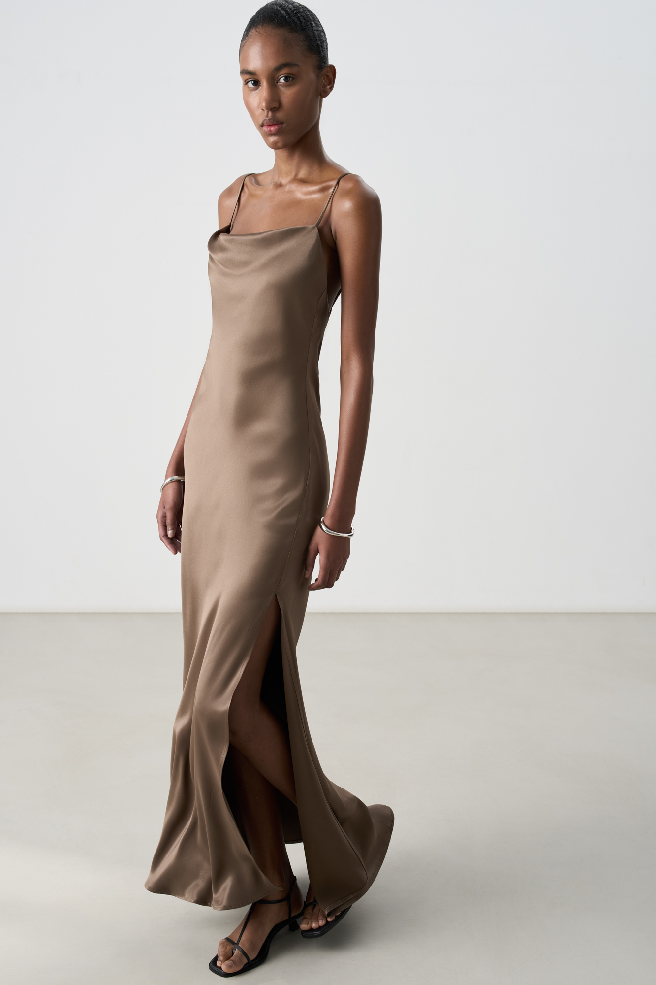 Атласное платье-комбинация длины миди из 100% вискозы. Модель приталенного силуэта, с высоким разрезом сбоку и открытой спиной. Изделие выполнено на тонких регулируемых бретелях.