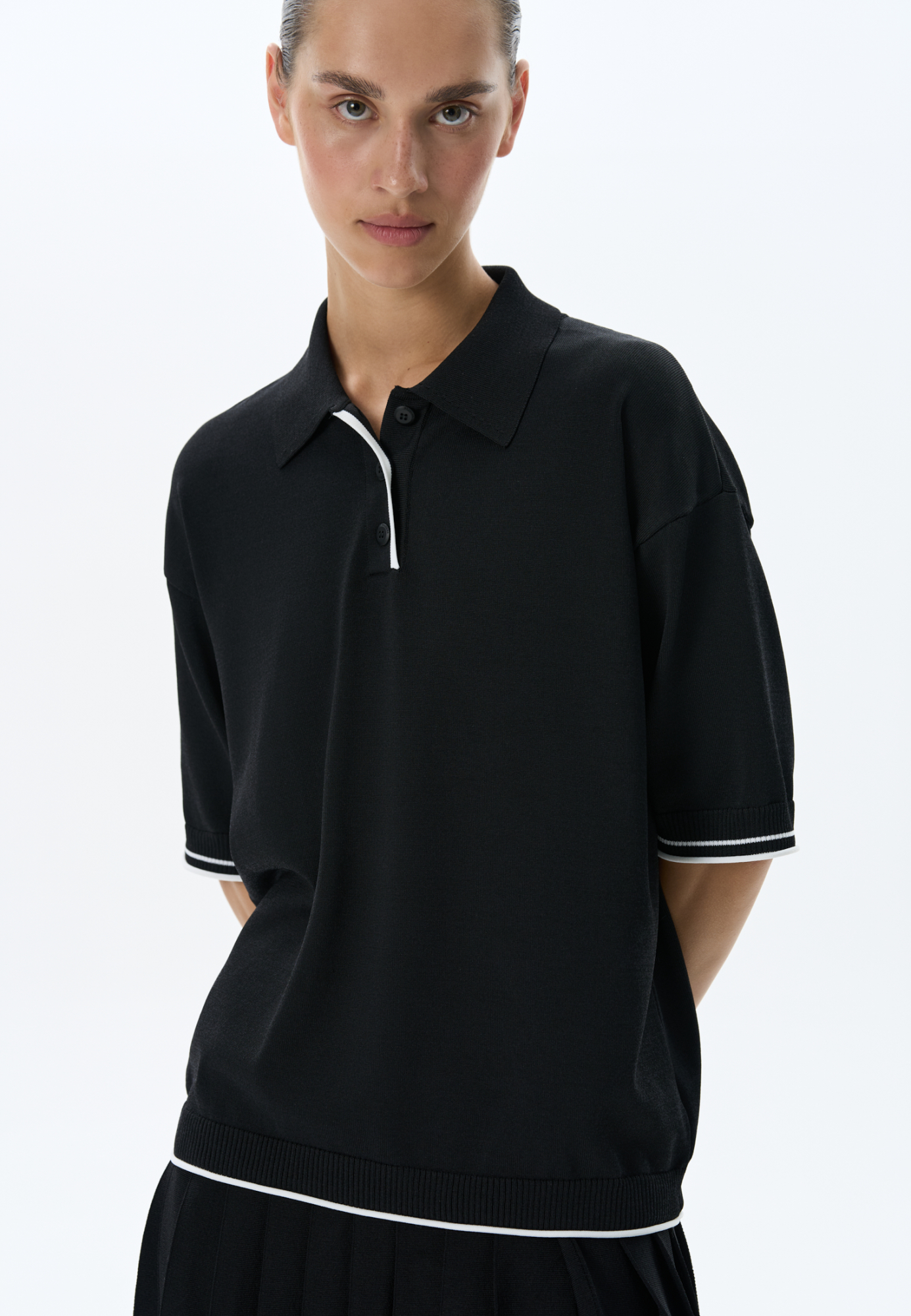 Трикотажная футболка поло из вискозы. Модель прямого силуэта, со спущенной линией плеч, короткими рукавами, отложным воротником-поло и планкой с тремя пуговицами. Рукава и нижний край изделия декорированы кантом контрастного цвета.