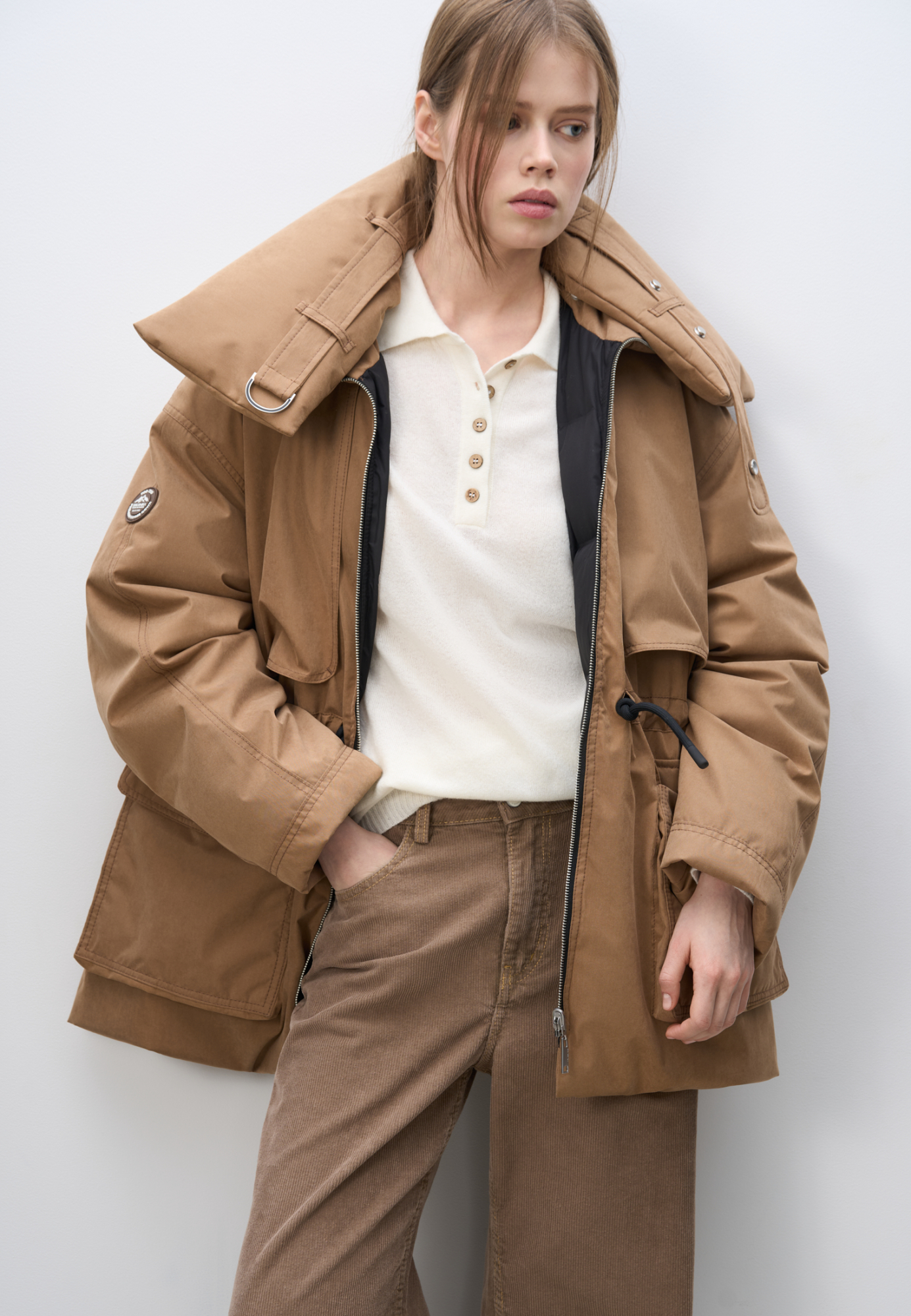 Двусторонний пуховик. Модель свободного силуэта с регулируемой кулиской на талии, большими накладными карманами с клапанами и воротником-стойкой. В комплекте к куртке идет дополнительный объемный воротник и капюшон. Застежка на молнию.