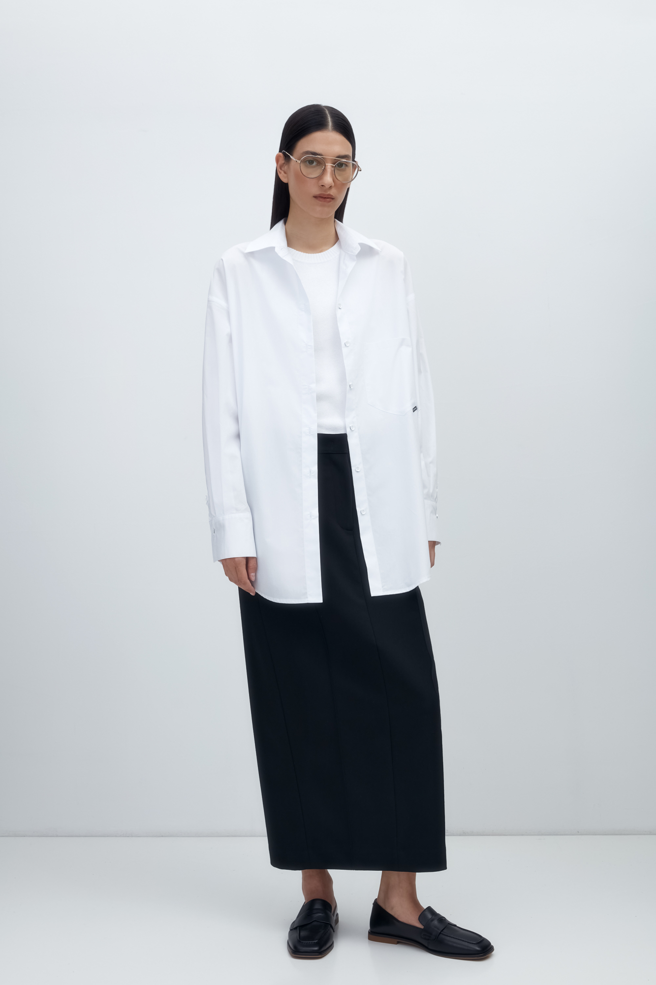 Рубашка с накладным карманом и брендированным ярлыком. Модель свободного силуэта, длинные рукава с манжетами и асимметричный нижний край.