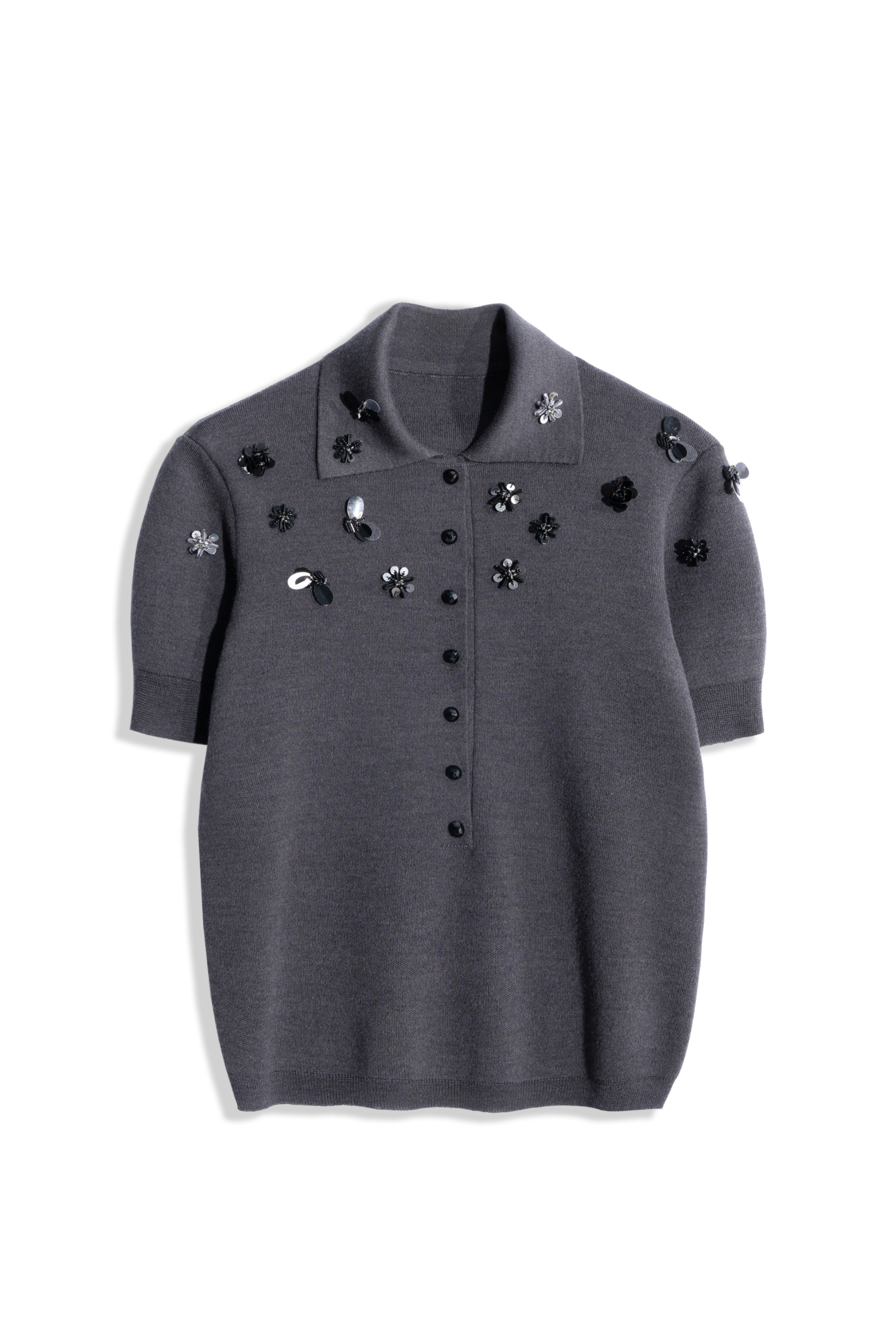 Трикотажная футболка поло из шерсти. Модель свободного силуэта с воротником поло и низкой планкой на пуговицах. Изделие декорировано цветами из бисера и пайеток.