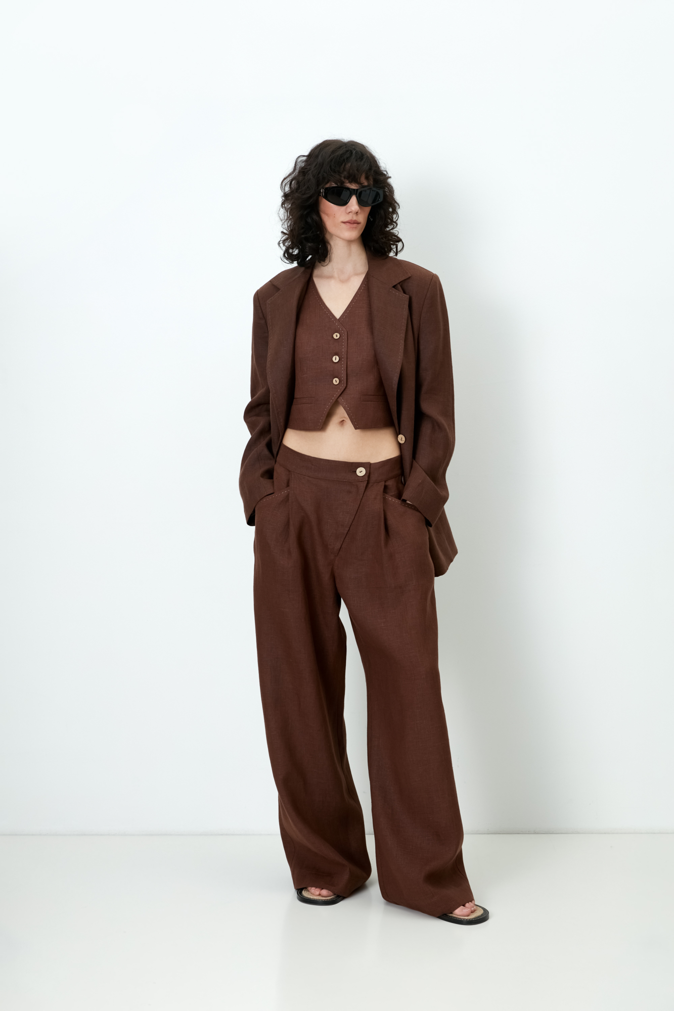 Брюки из 100% льна. Модель прямого кроя, с высокой посадкой, косой застежкой на пуговицу и молнию, боковыми карманами.