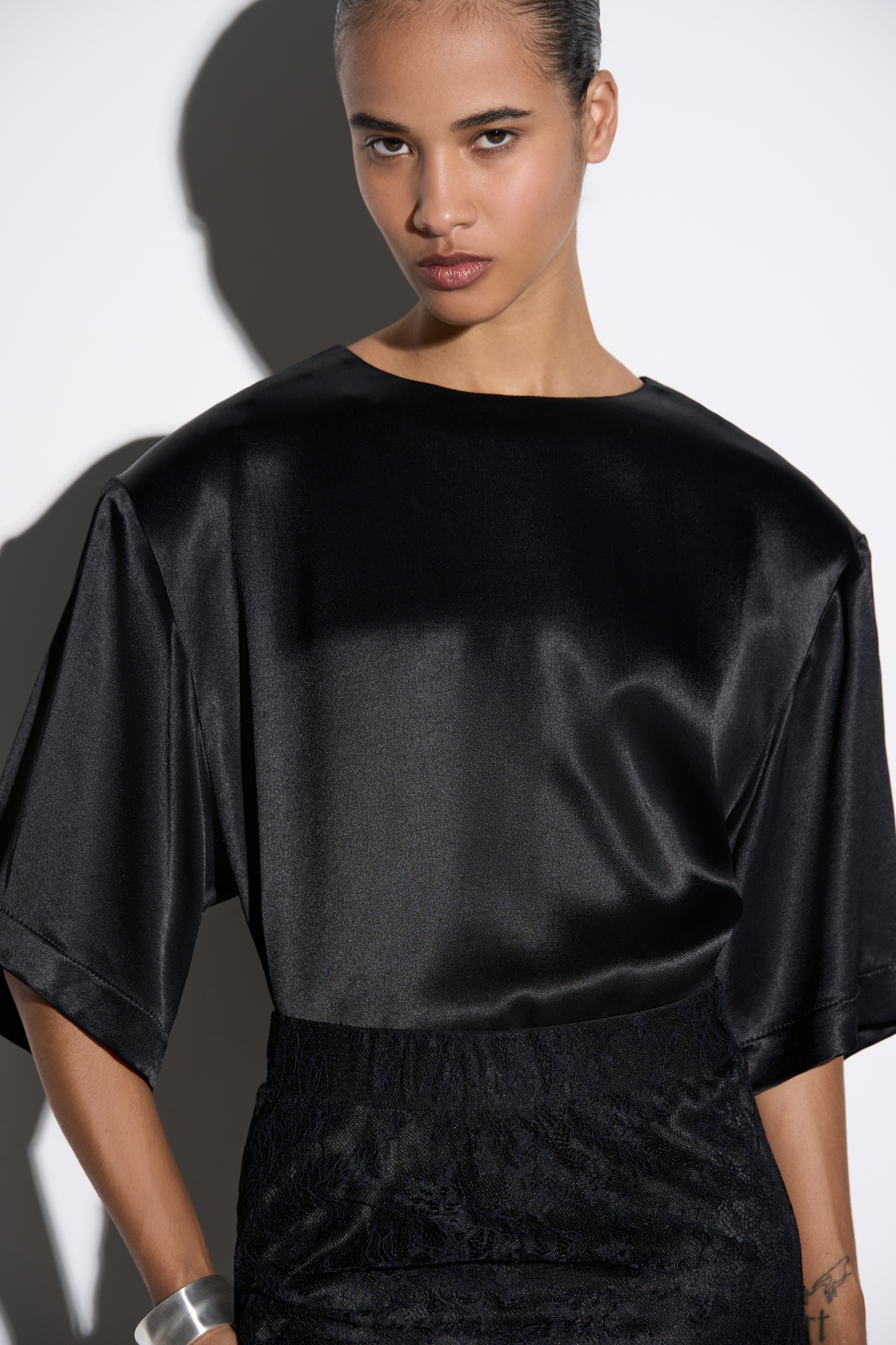Удлиненная футболка из 100% атласной вискозы. Модель свободного силуэта с подплечниками и широкими рукавами.