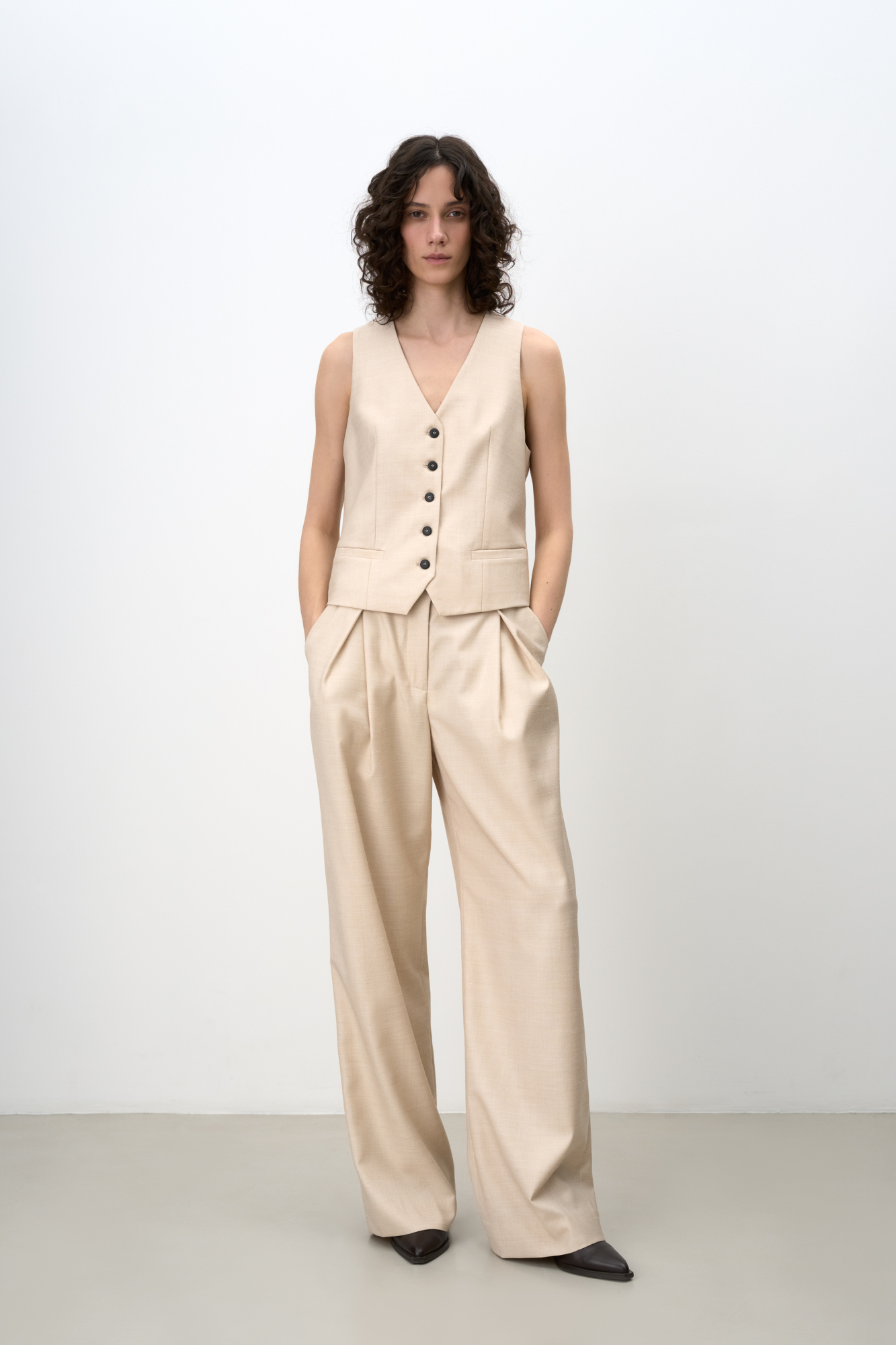 Классические брюки из смесовой шерсти с текстурой. Модель прямого кроя с косыми складками и объемными защипами спереди, шлевками на поясе для ремня и карманами. Застежка на молнию и скрытую пуговицу. Дополнить образ можно жакетом и жилетом в таком же стиле.