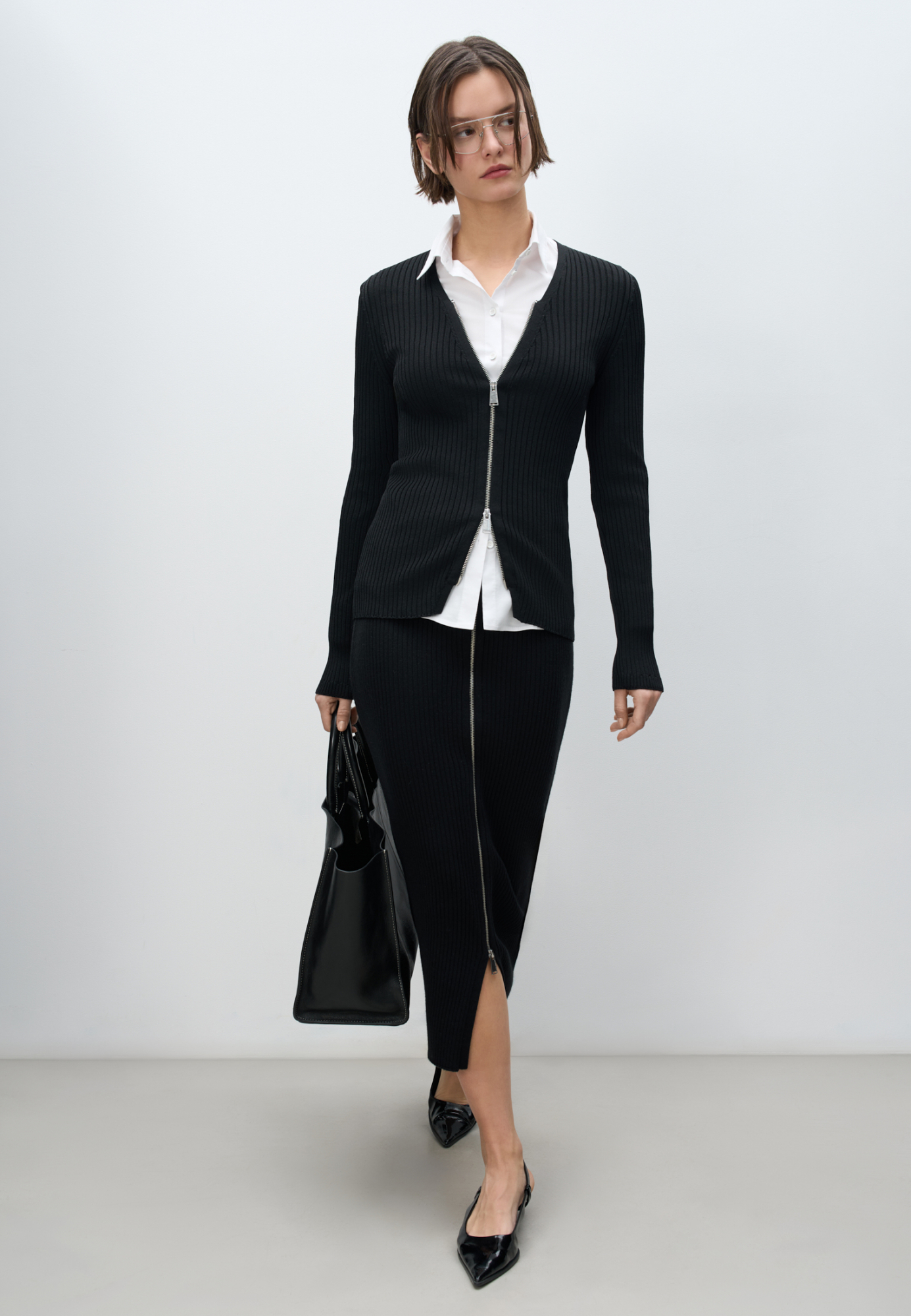 Трикотажная юбка длины макси с разрезом спереди. Модель по фигуре с широким эластичным поясом. Изделие декорировано молнией с крупной фурнитурой.