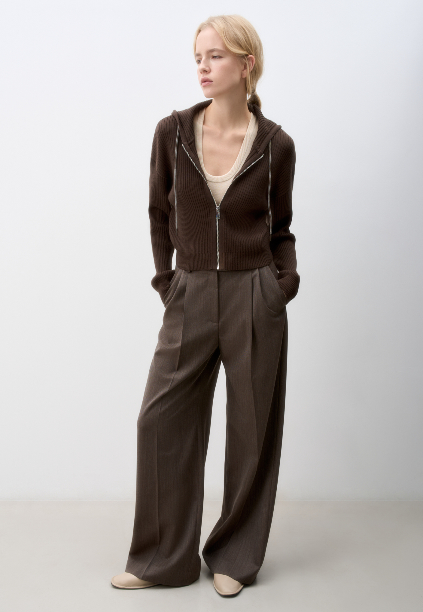 Короткий трикотажный бомбер из шерсти. Модель свободного силуэта, со спущенной линией пллеч, длинными рукавами и капюшоном с кулиской. Низ изделия и манжеты рукавов выполнены на эластичной резинке. Застежка на молнию.