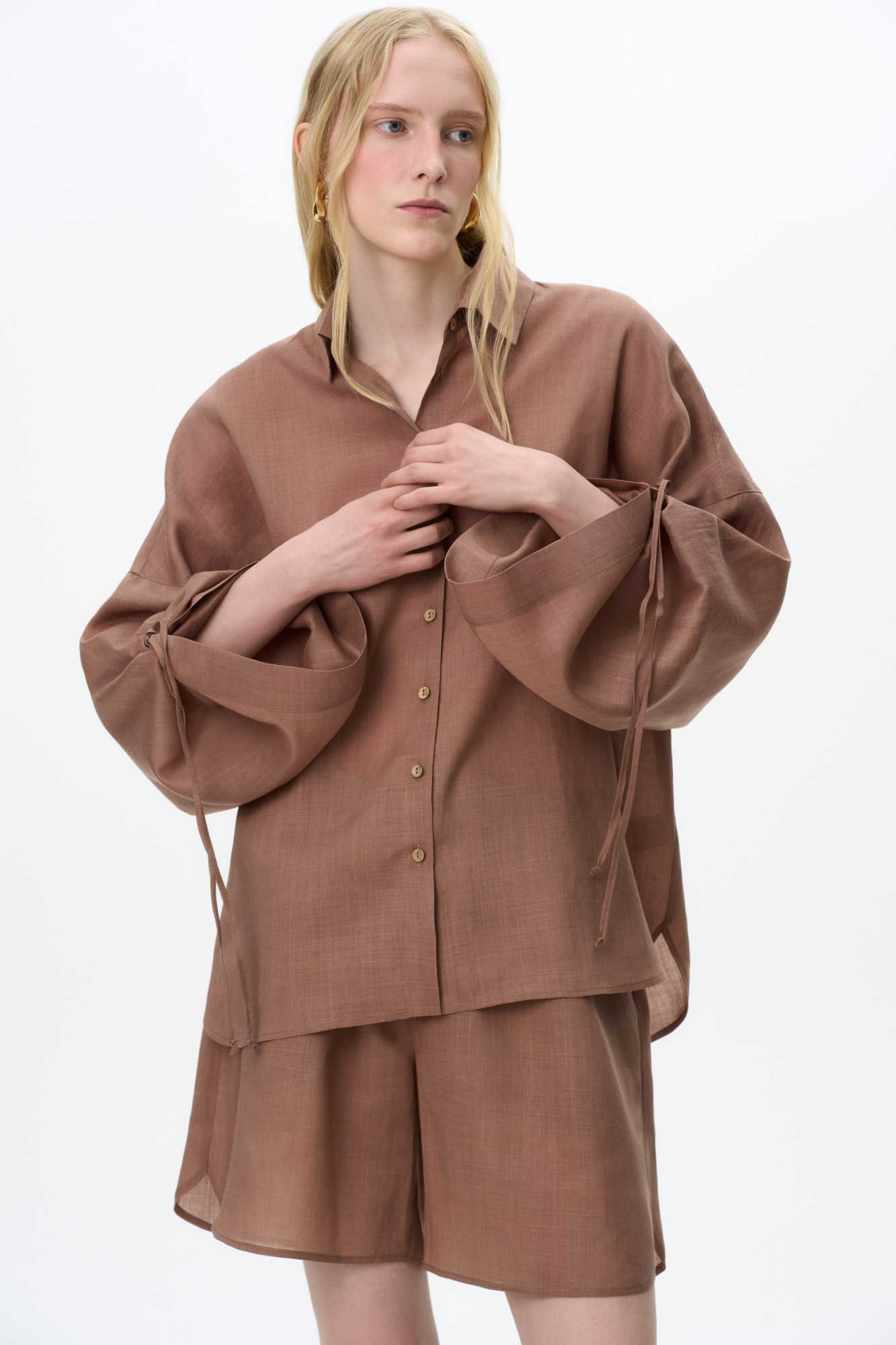 Комплект из 100% крапивы, состоящий из рубашки и шорт. Рубашка с длинными расклешенными рукавами на кулиске, классическим отложным воротником и застежкой на пуговицы. Короткие шорты&nbsp;&nbsp;с боковыми карманами и эластичным поясом на резинке.