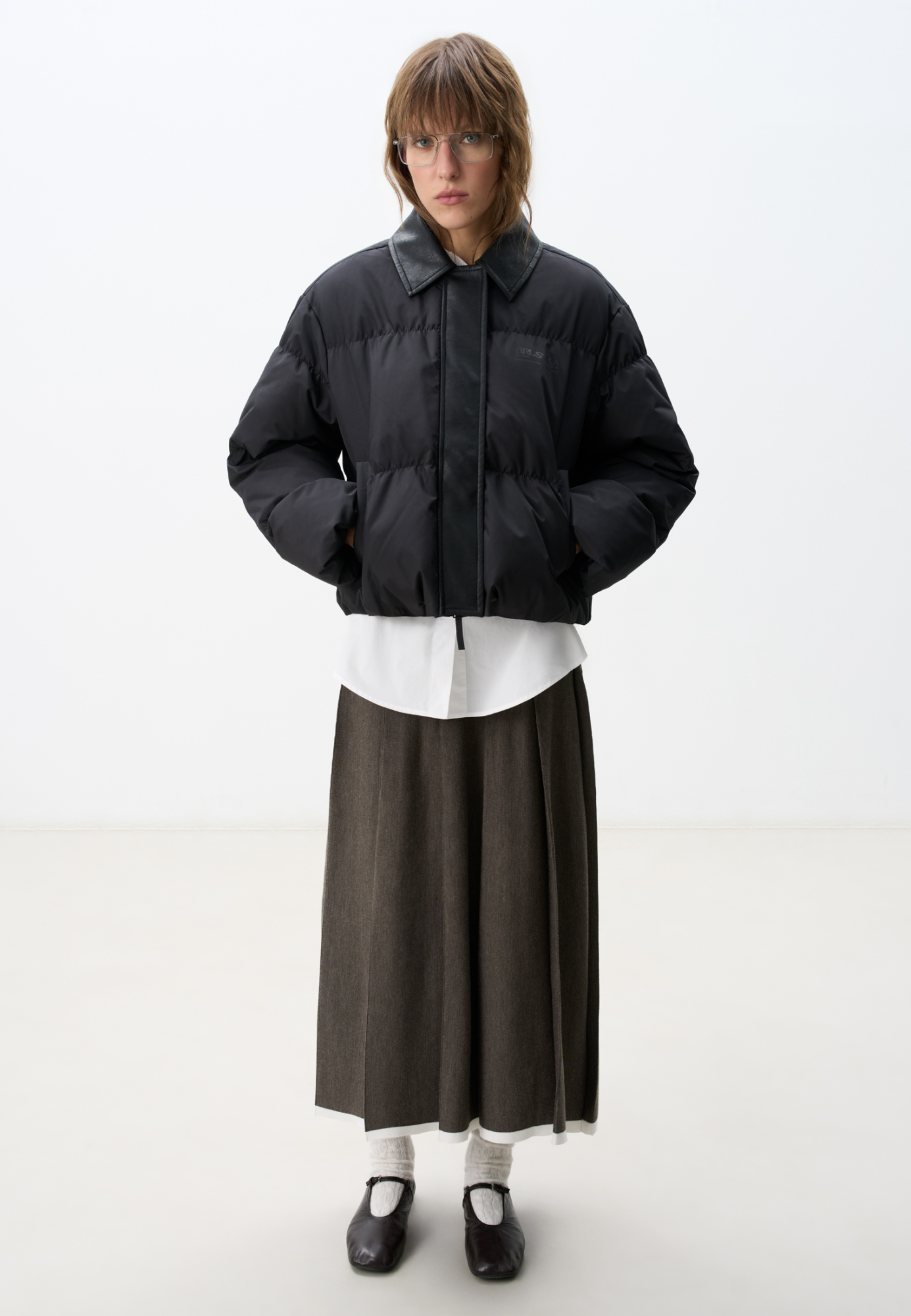 Стеганый пуховик с отложным воротником из экокожи. Модель свободного силуэта со спущенной линией плеч и боковыми карманами. Застежка на молнию и магнитные кнопки под вертикальной планкой из экокожи. Логотип на груди. Изделие выполнено на подкладке.