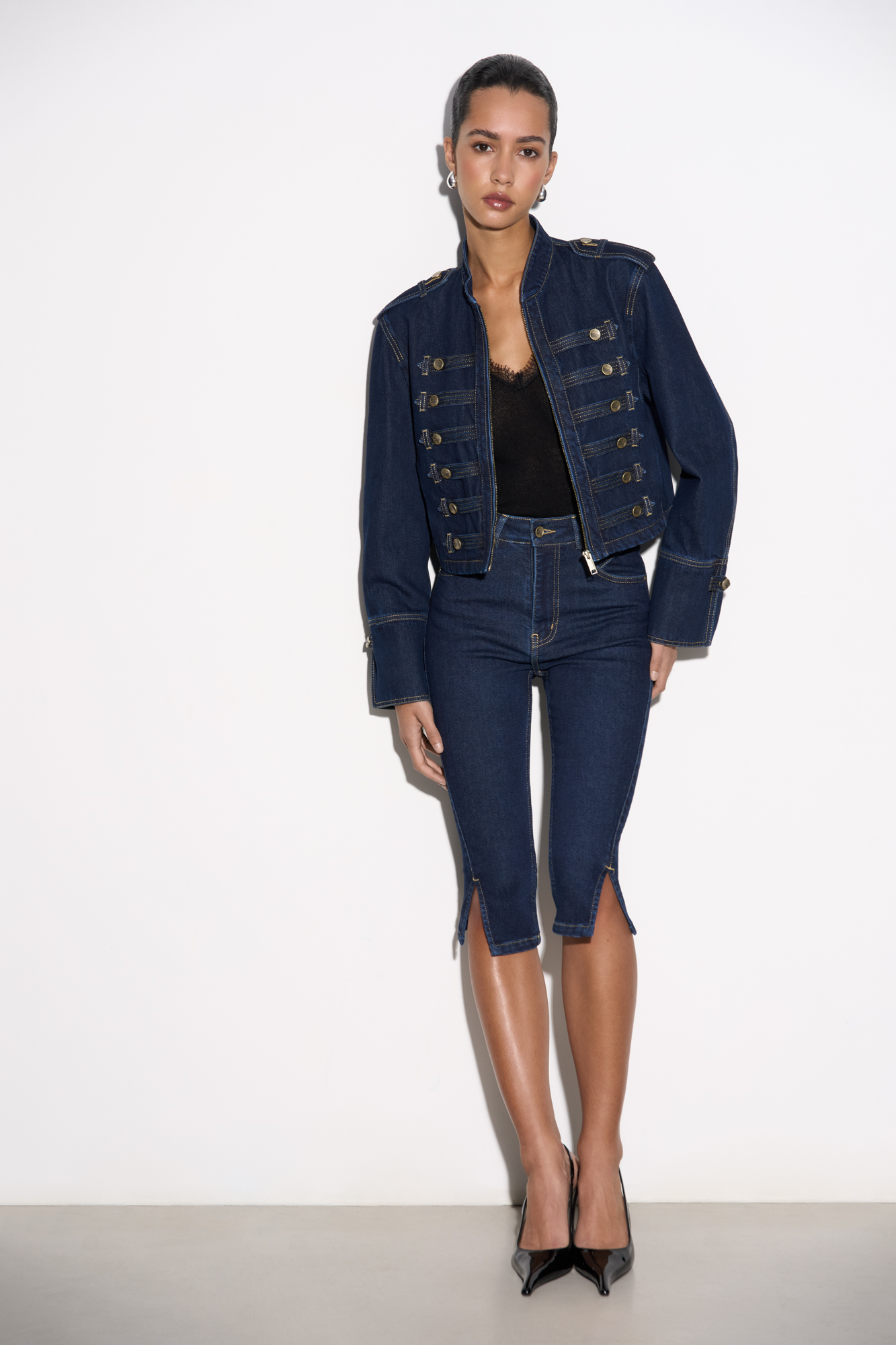 Джинсовые бриджи слим фит с высокой посадкой. Модель по фигуре с декоративной отстрочкой на поясе и невымокими разрезами сбоку. Четыре кармана, застежка на молнию и металлическую пуговицу.