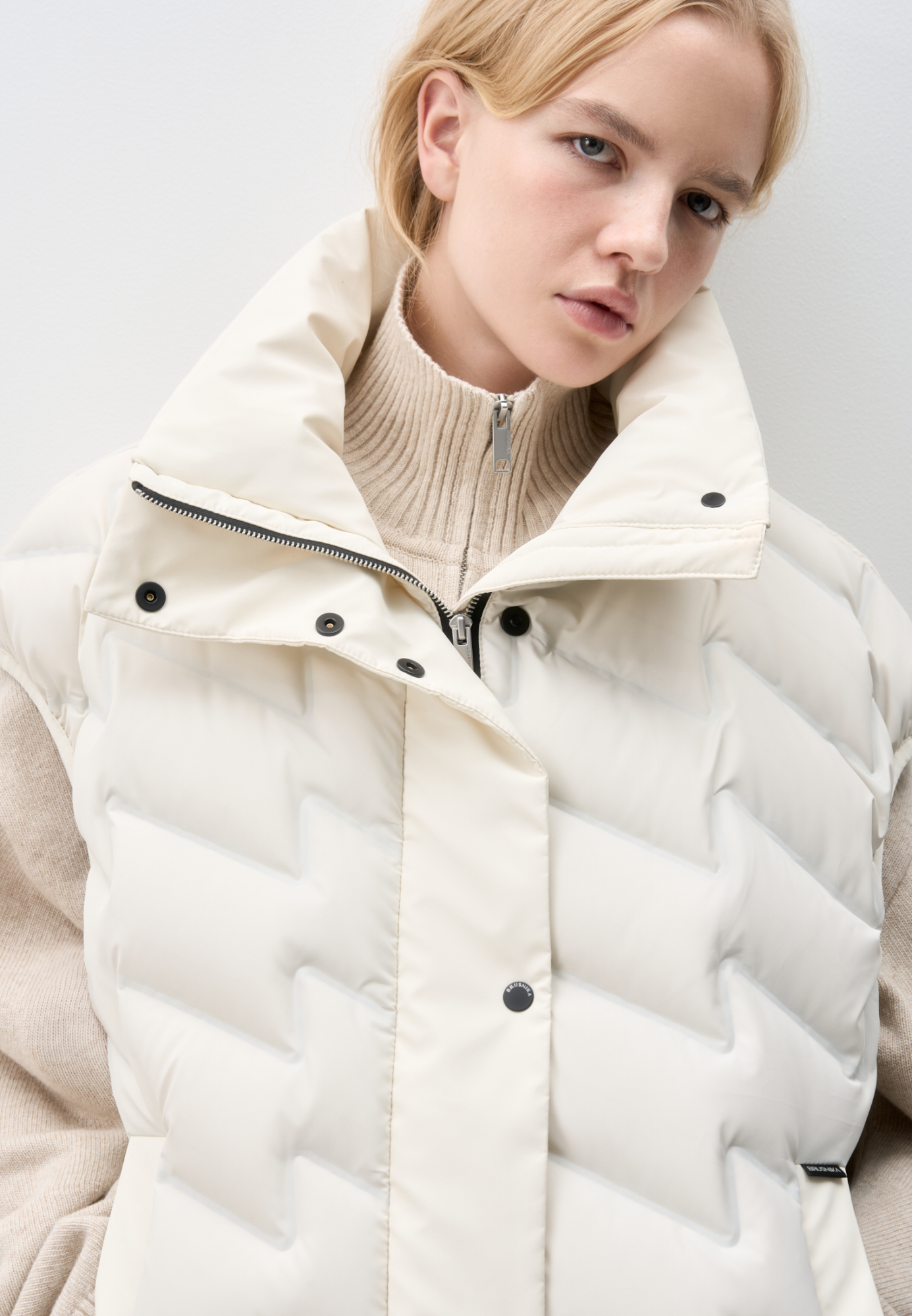 Объемный стеганый жилет на пуху. Модель прямого кроя, с воротником стойкой и боковыми карманами. Застежка на молнию и кнопки под планкой.