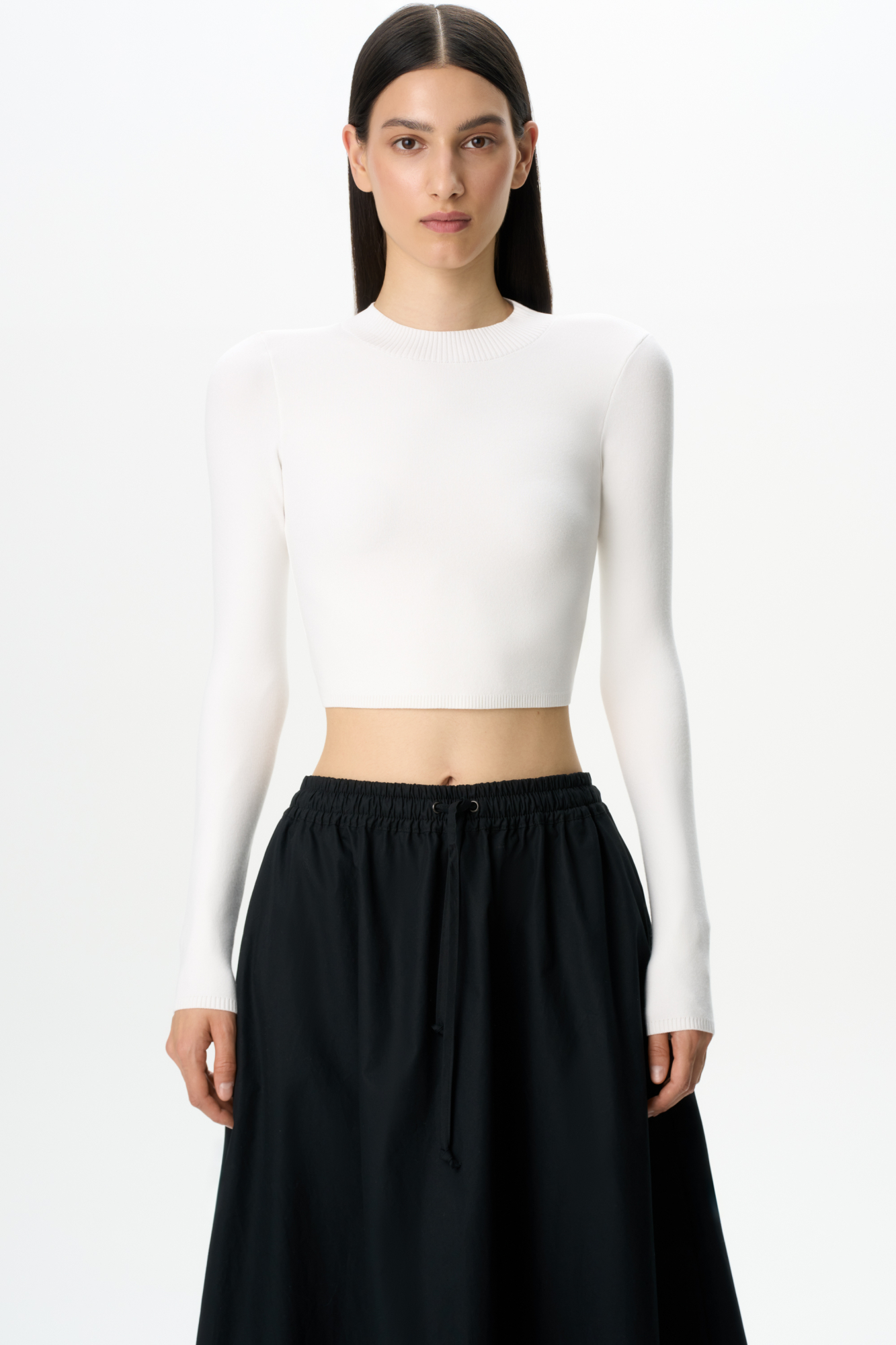 Трикотажный кроп-топ из вискозы с длинным рукавом, круглым вырезом горловины и фигурным низом. Края изделия выполнены в рубчик.