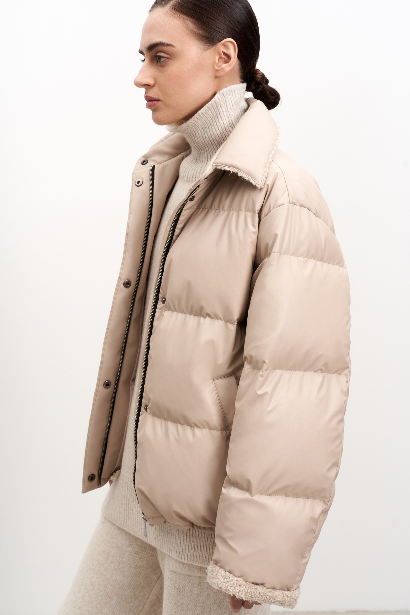 Утепленый пуховик из экокожи. Модель свободного силуэта с боковыми карманами и воротником-стойкой. Застежка на потайную молнию и кнопки. На подкладке.