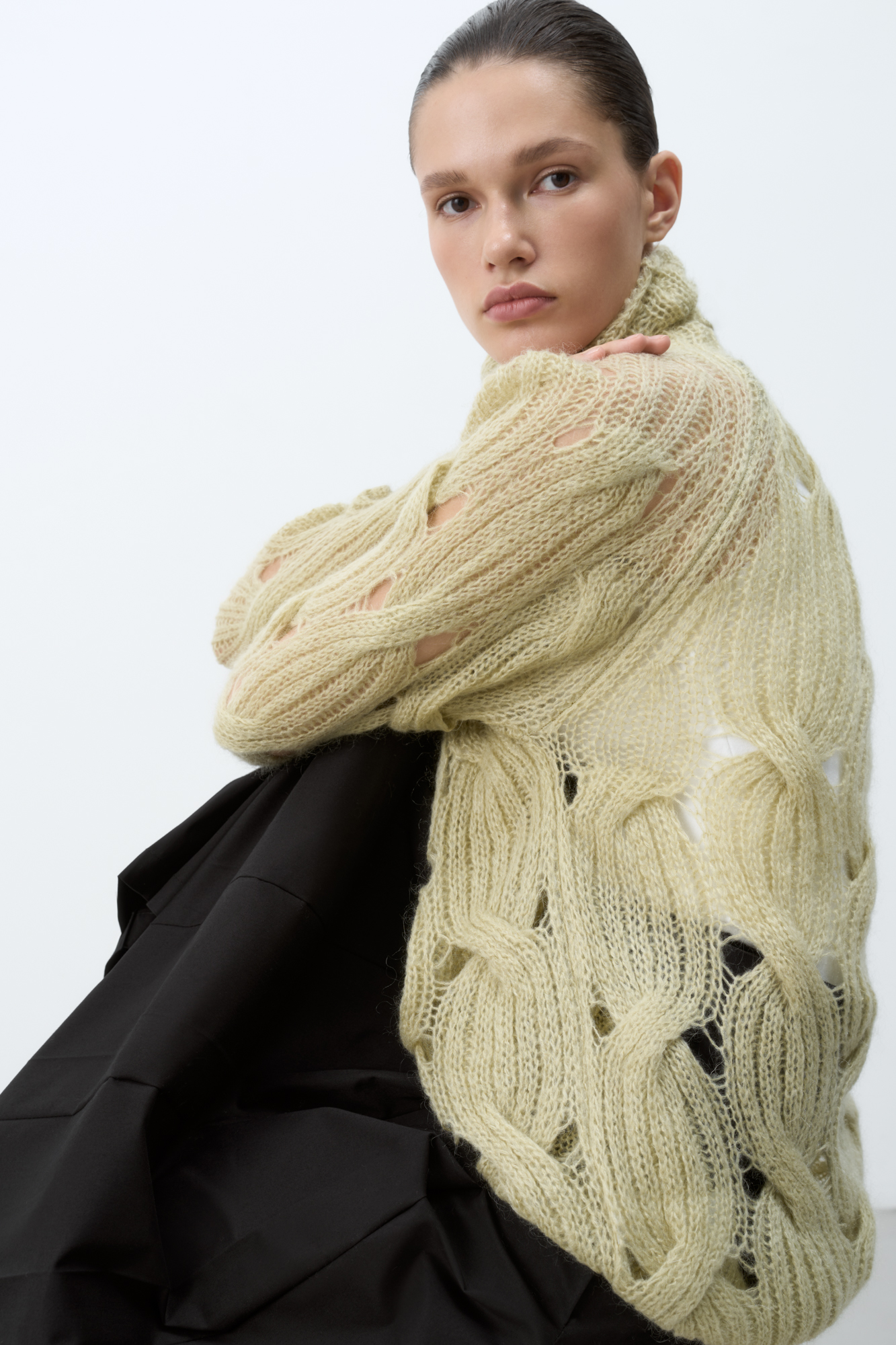 Объемный удлиненный джемпер с мохером, вязка выполнена крупными косами. Высокий ворот под горло. Манжеты рукавов и низ изделия на резинке. 