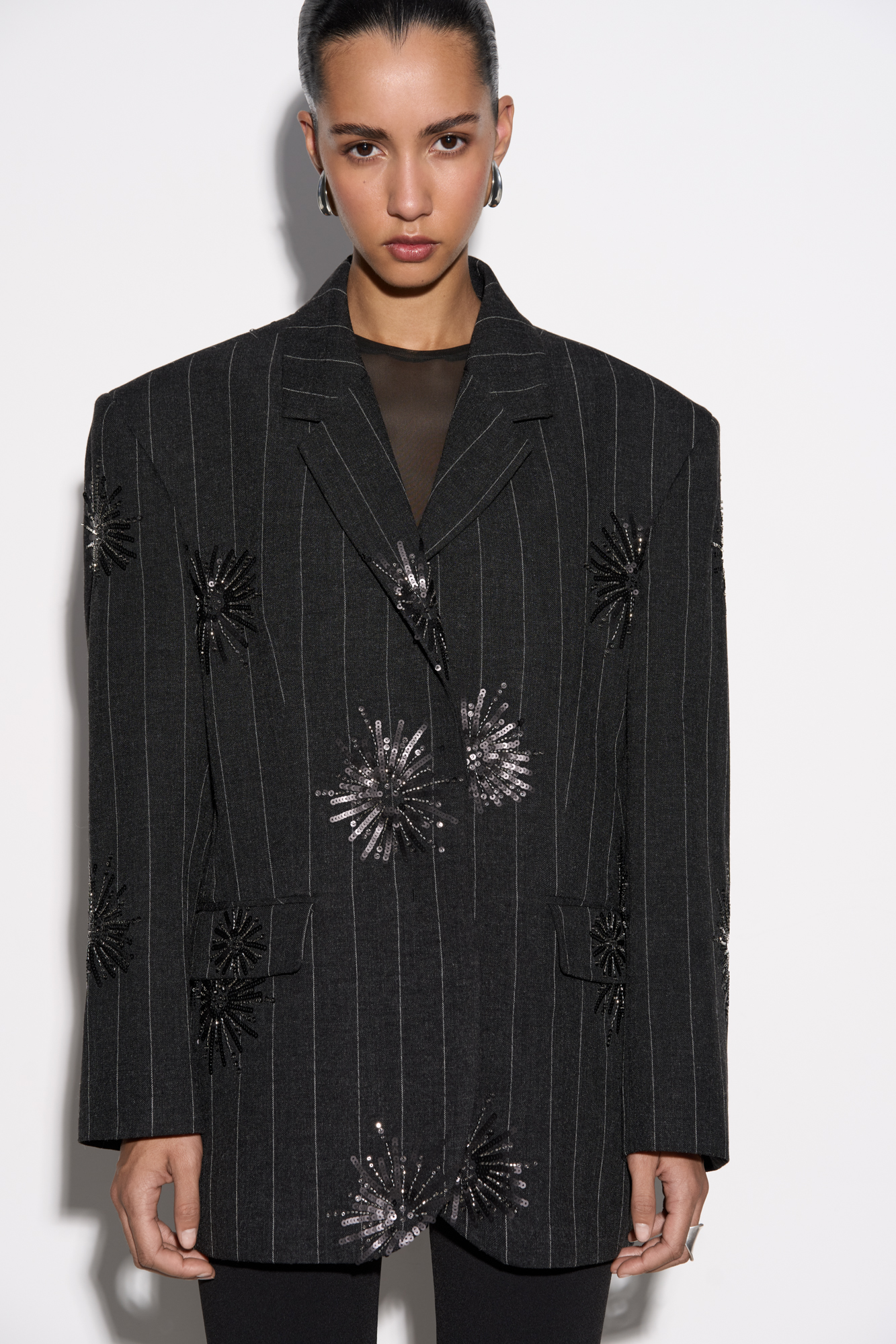Однобортный жакет из шерсти, декорированный узором из пайеток. Модель прямого кроя с узкими лацканами, широкими плечами, боковыми карманами с клапанами и застежкой на две пуговицы. Изделие выполнено на подкладке.