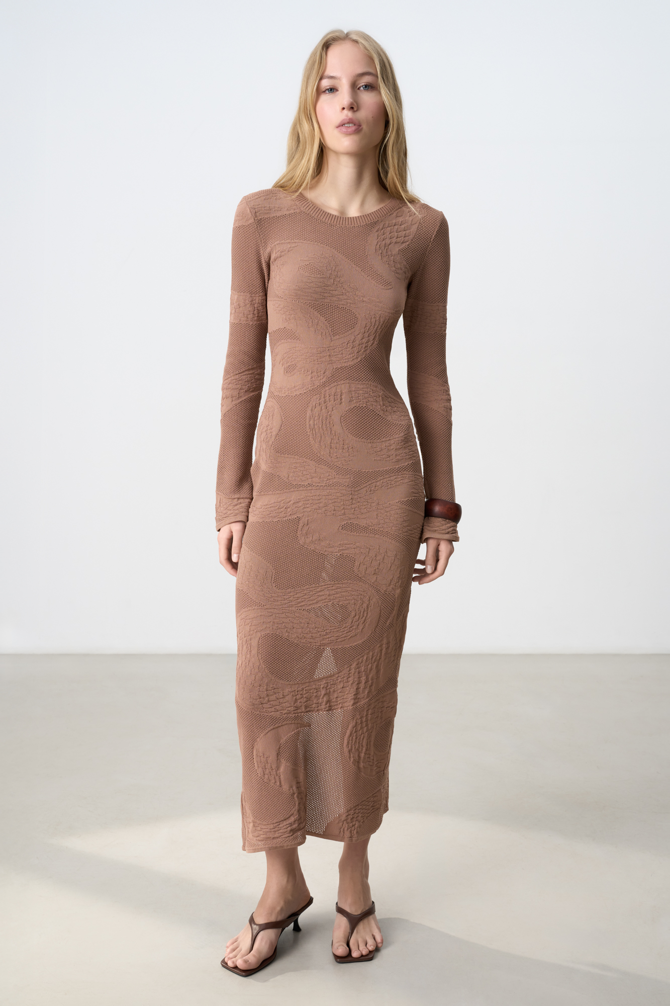 Трикотажное платье длины макси из хлопка. Модель приталенного силуэта с круглым вырезом горловны и длинным рукавом. Изделие декорировано жаккардовым узором в виде змеи. <br />
Органический хлопок - более экологичная и безопасная альтернатива обычному хлопку, выращенная без использования химикатов.