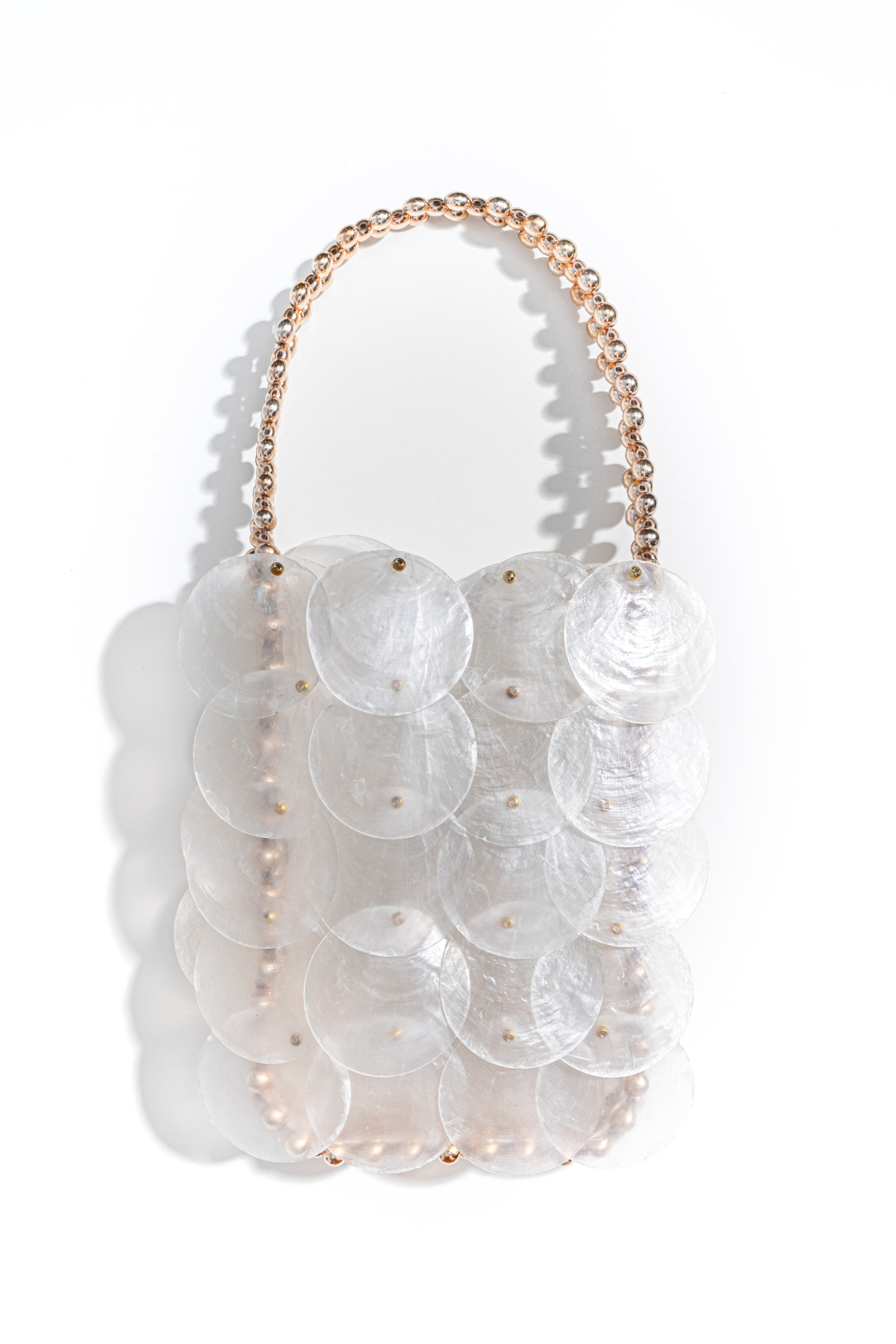 Сумочка, выполненная путем переплетения полупрозрачных перламутровых пайеток и золотых бусин. Модель с маленькой ручкой. Высота изделия составляет 18 см, длина ручки - 13 см, длина цепочки - 110 см. 