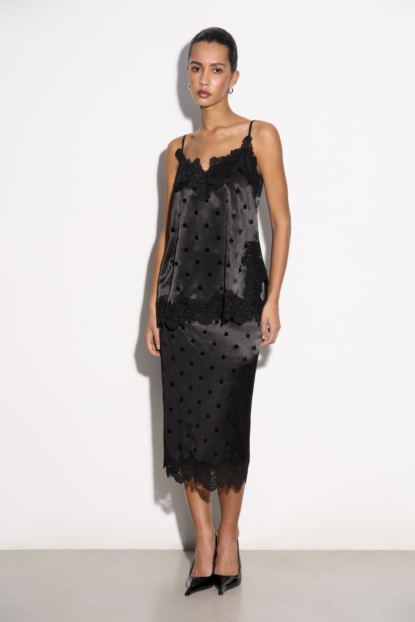 Атласная юбка в горох длины миди. Модель по фигуре с застежкой на&nbsp;&nbsp;потайную молнию. Подол изделия декорирован кружевом.