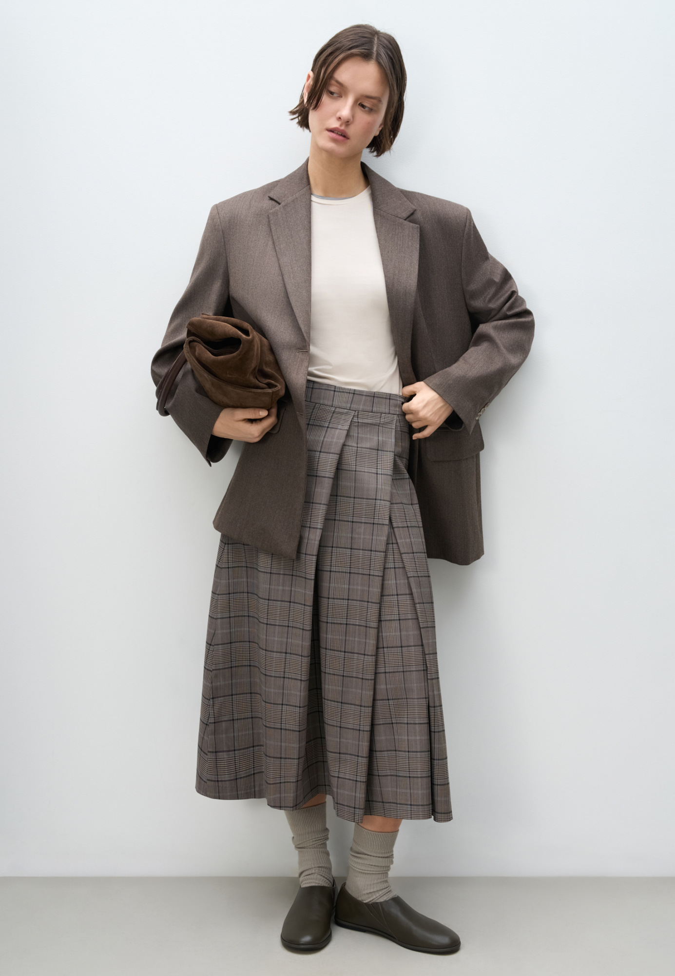 Юбка длины миди из шерсти в клетку. Модель А-силуэта с крупными косыми складками спереди. Застежка на молнию сзади. Изделие без подкладки.