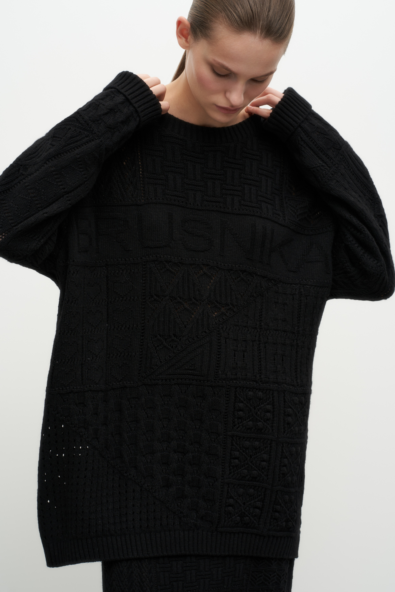 Трикотажный джемпер из смесовой шерсти. Модель свободного силуэта со спущенным плечом и ажурным переплетением. Дополнить образ можно юбкой или шортами в таком же стиле. 