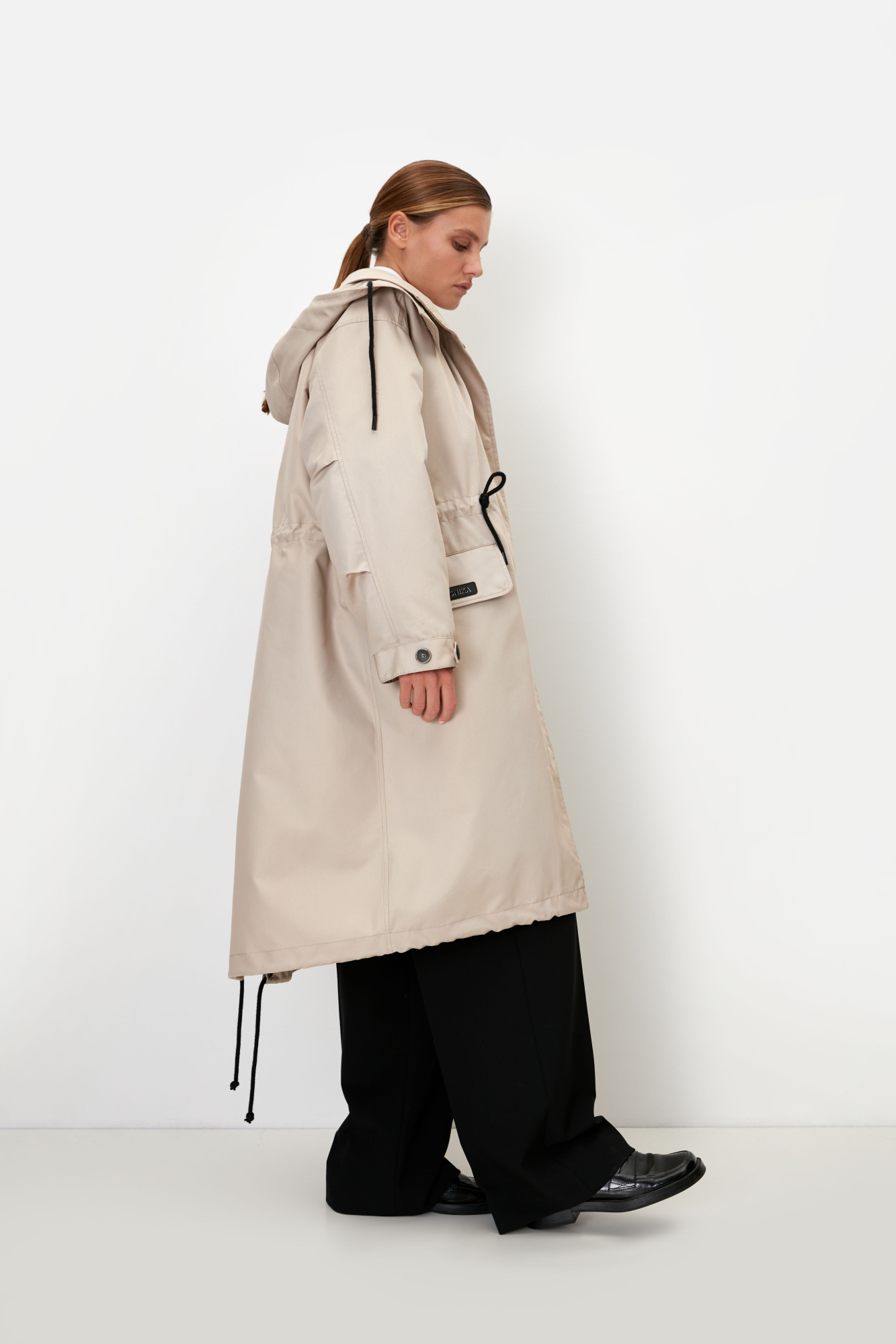 Парка с накладными карманами, воротником-стойка и капюшоном на пуговицах. Съемная стеганая подкладка, выполненаная из натурального пух-пера. Потайная застежка на молнии и кнопках. Для фиксации кулиска на поясе и капюшоне. Средний показатель водонепроницаемости, можно носить в сухую погоду или моросящий дождик.